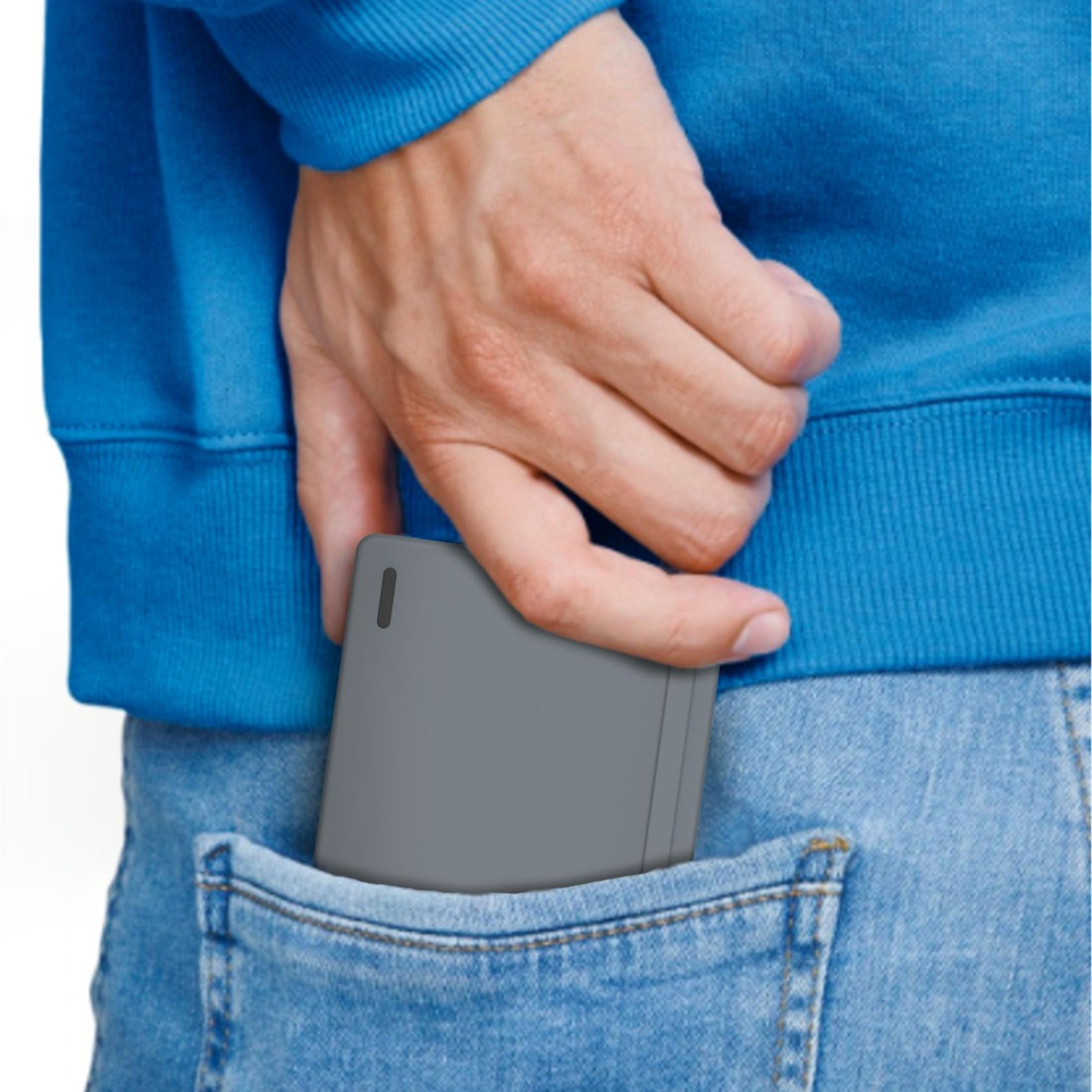 La mano di una persona in una tasca di jeans. La persona tiene in mano un oggetto grigio di forma quadrata.