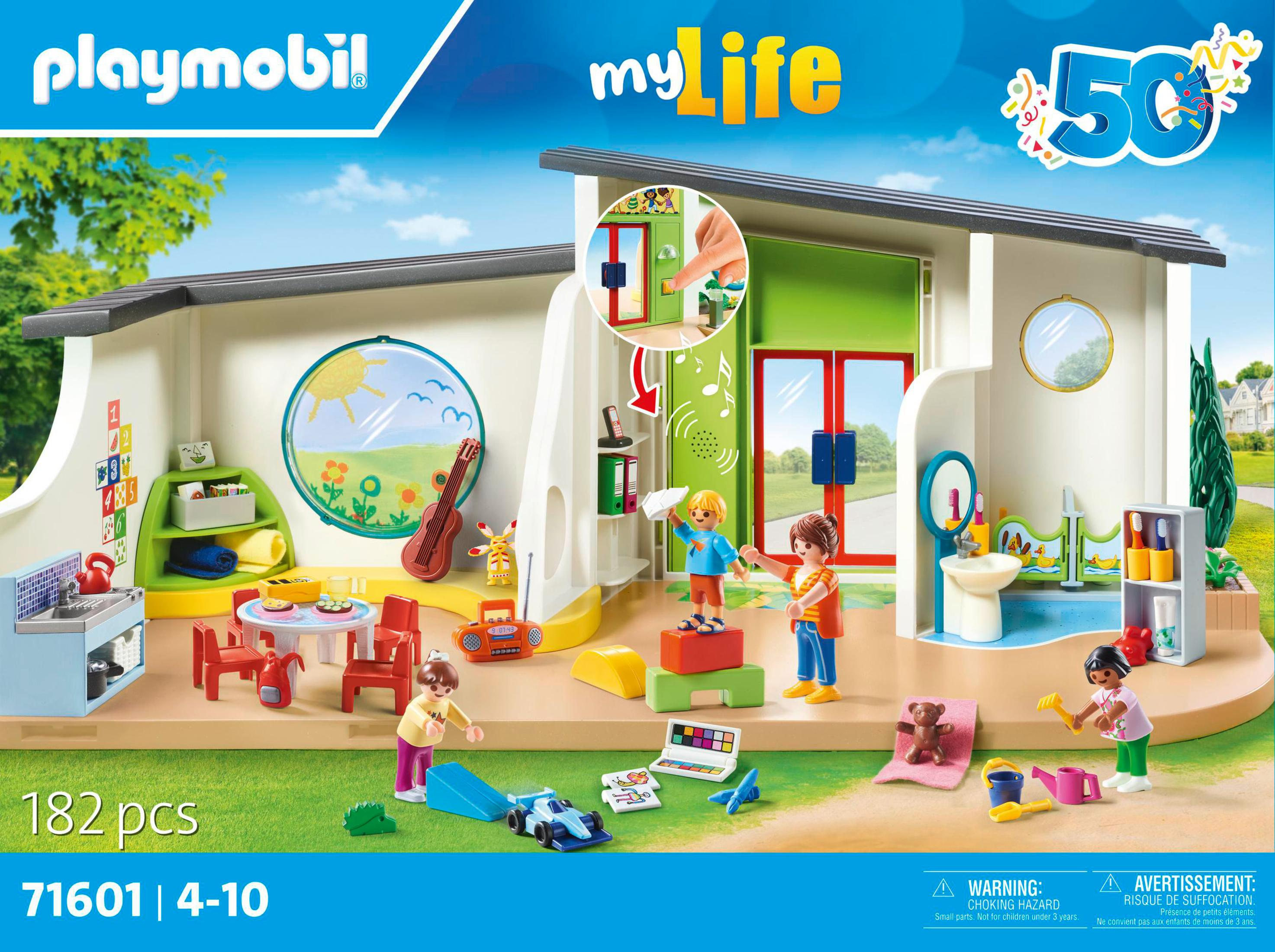 Set Playmobil raffigurante un asilo nido con bambini che giocano, un tavolo, una chitarra e un lavandino. Alberi.