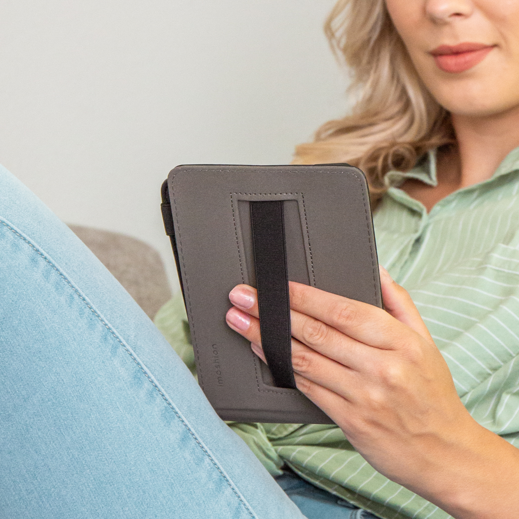 Een vrouw leest een boek met een grijze omslag, zittend op een bank, groen overhemd.