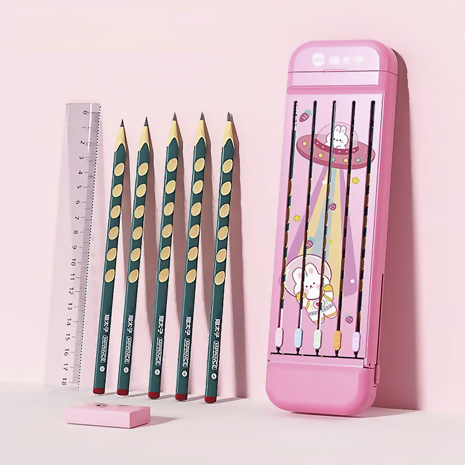 Un estuche rosa con lápices, una regla y una goma de borrar sobre un fondo rosa. Hay un diseño de dibujos animados.