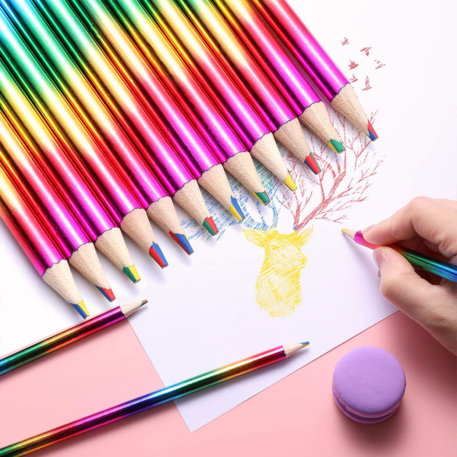 Lápices de colores arcoíris sobre papel blanco, un dibujo y una goma de borrar morada.