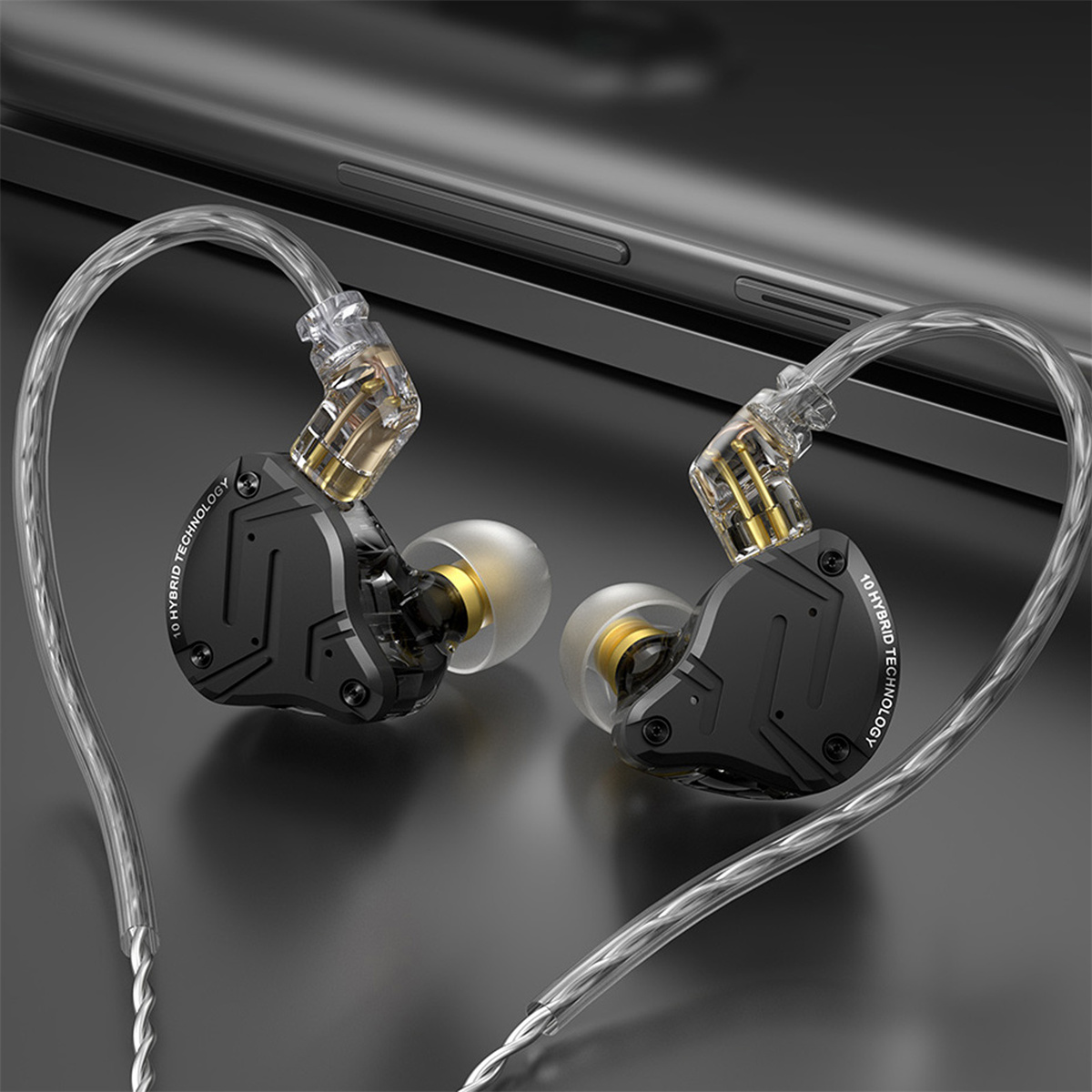 Schwarze und goldene In-Ear-Kopfhörer, mit transparenten Kabeln, auf dunkler Oberfläche.