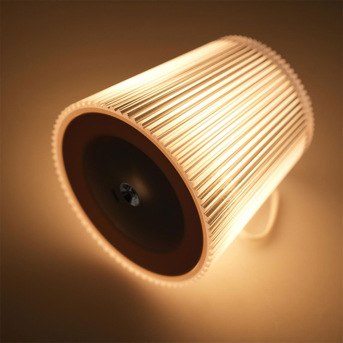 Eine moderne Lampe mit kreisförmigem Design. Sie hat einen gerippten Schirm und wirft ein warmes Licht. Schräge Ansicht.