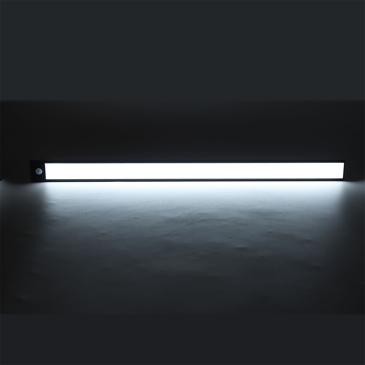 Eine helle, lange, weiße LED-Leuchte ist beleuchtet. Der Hintergrund ist eine dunkle, graue Oberfläche.