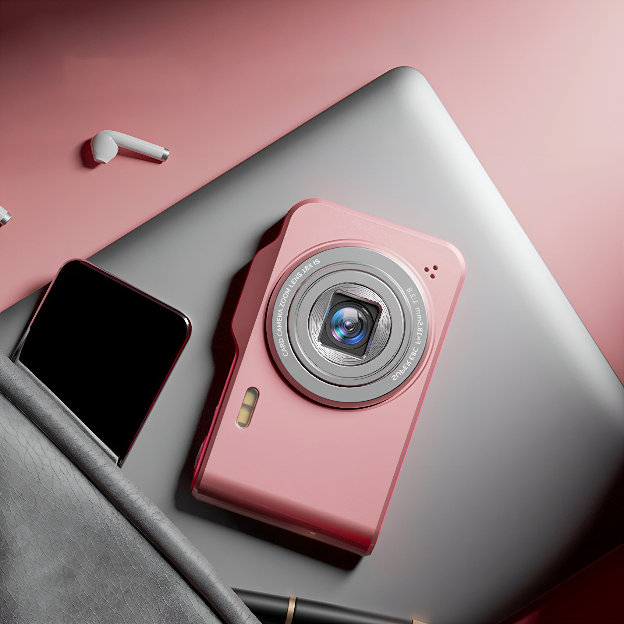 Eine rosa Kamera, Telefon und Ohrhörer liegen auf einem grauen Laptop auf rosa Oberfläche.