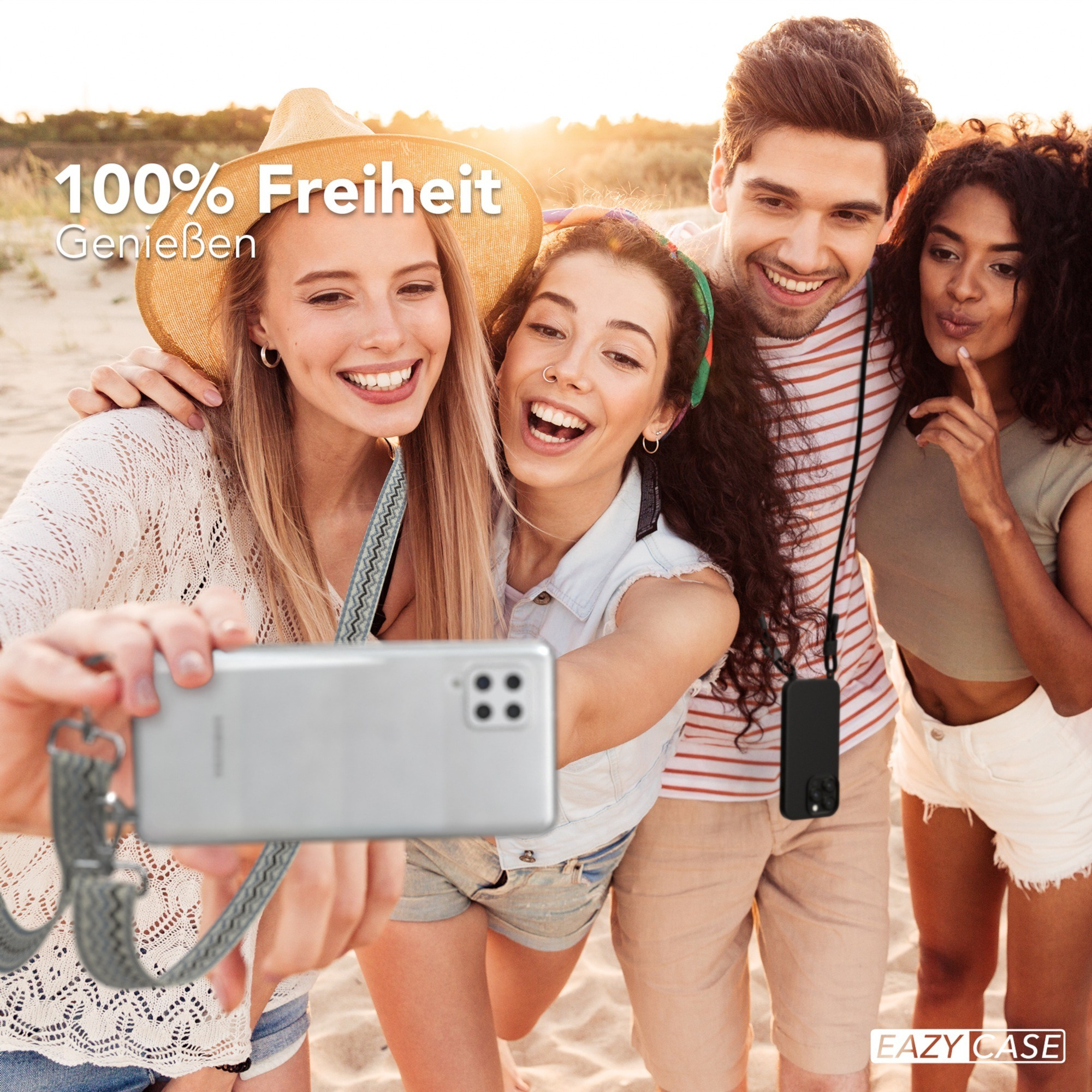 Vier lächelnde Personen, die ein Selfie am Strand mit einem Telefon und einem Lanyard machen.