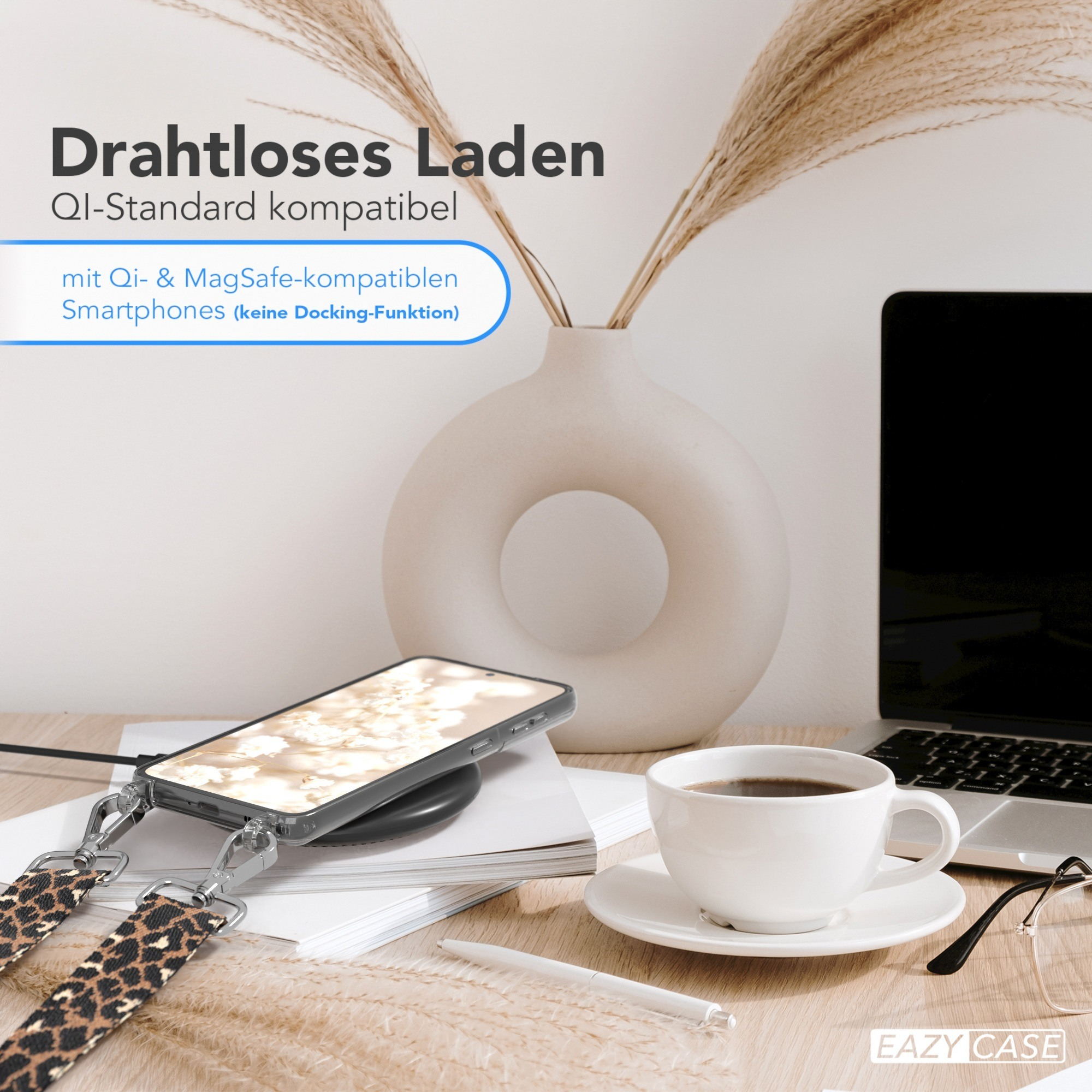 Ein Telefon mit Hülle, auf einem Ladepad, mit einer Tasse Kaffee und anderen Gegenständen auf einem Schreibtisch.