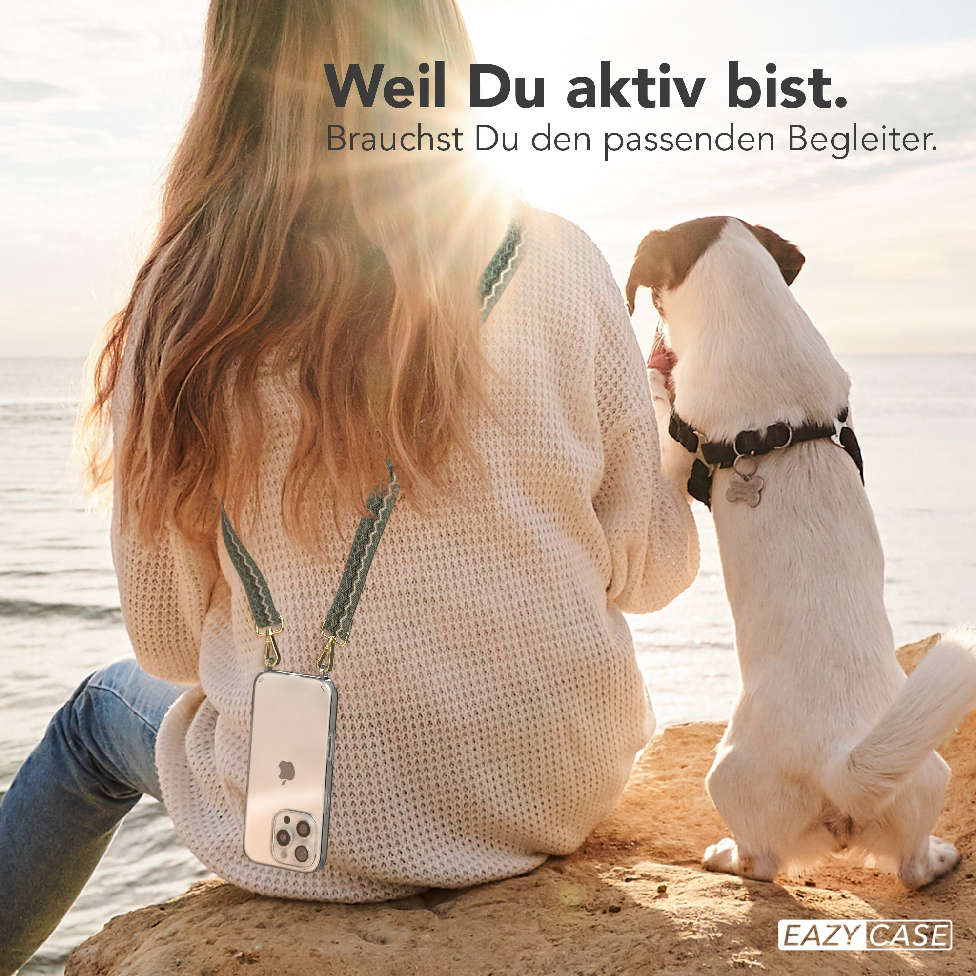 Frau mit Handy, Hund. Frau sitzt auf Felsen, Hund steht. Sonne im Hintergrund. Handyhülle am Gurt befestigt.