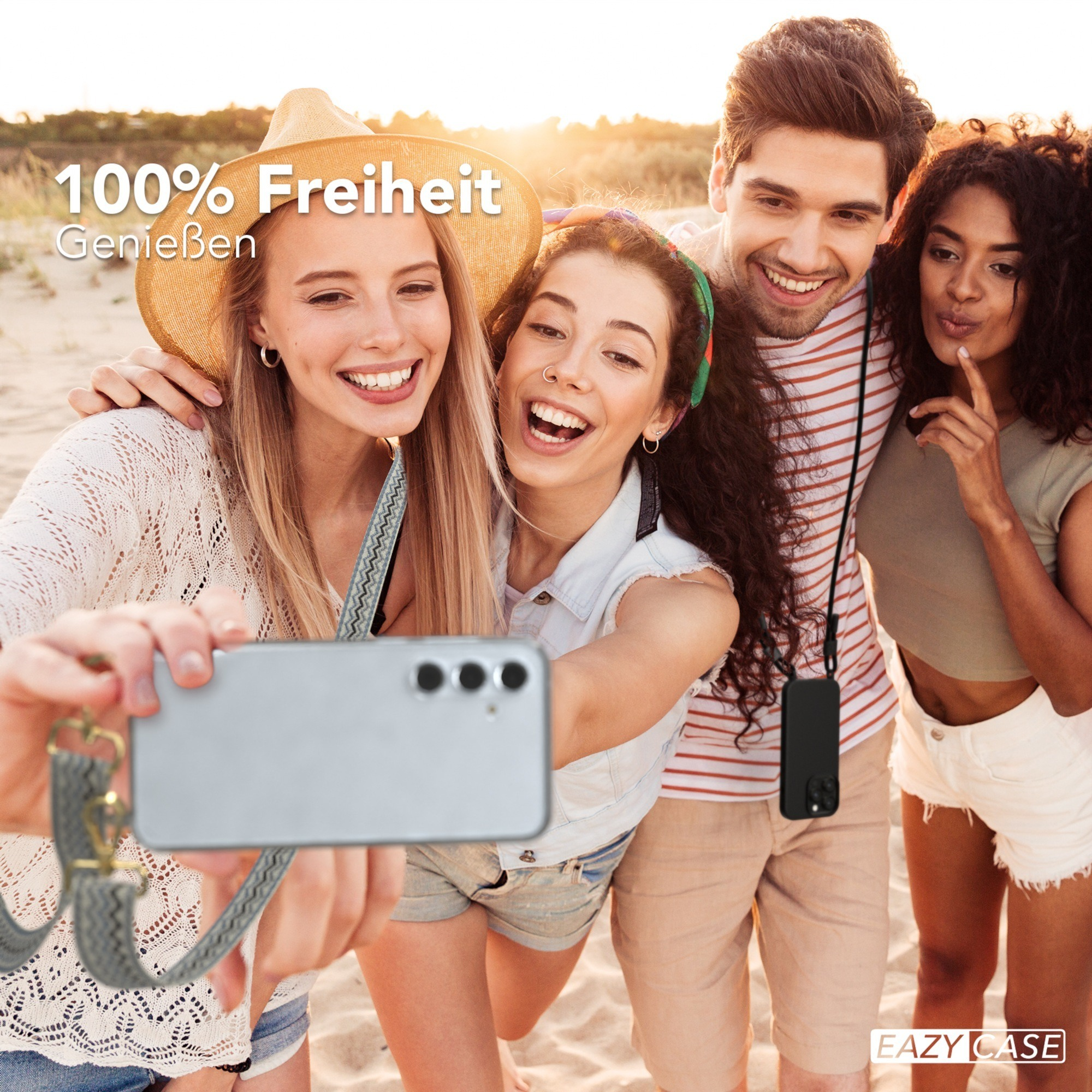 Vier Personen machen ein Selfie. Sie lächeln und halten ein Telefon. Im Hintergrund ist ein Strand.
