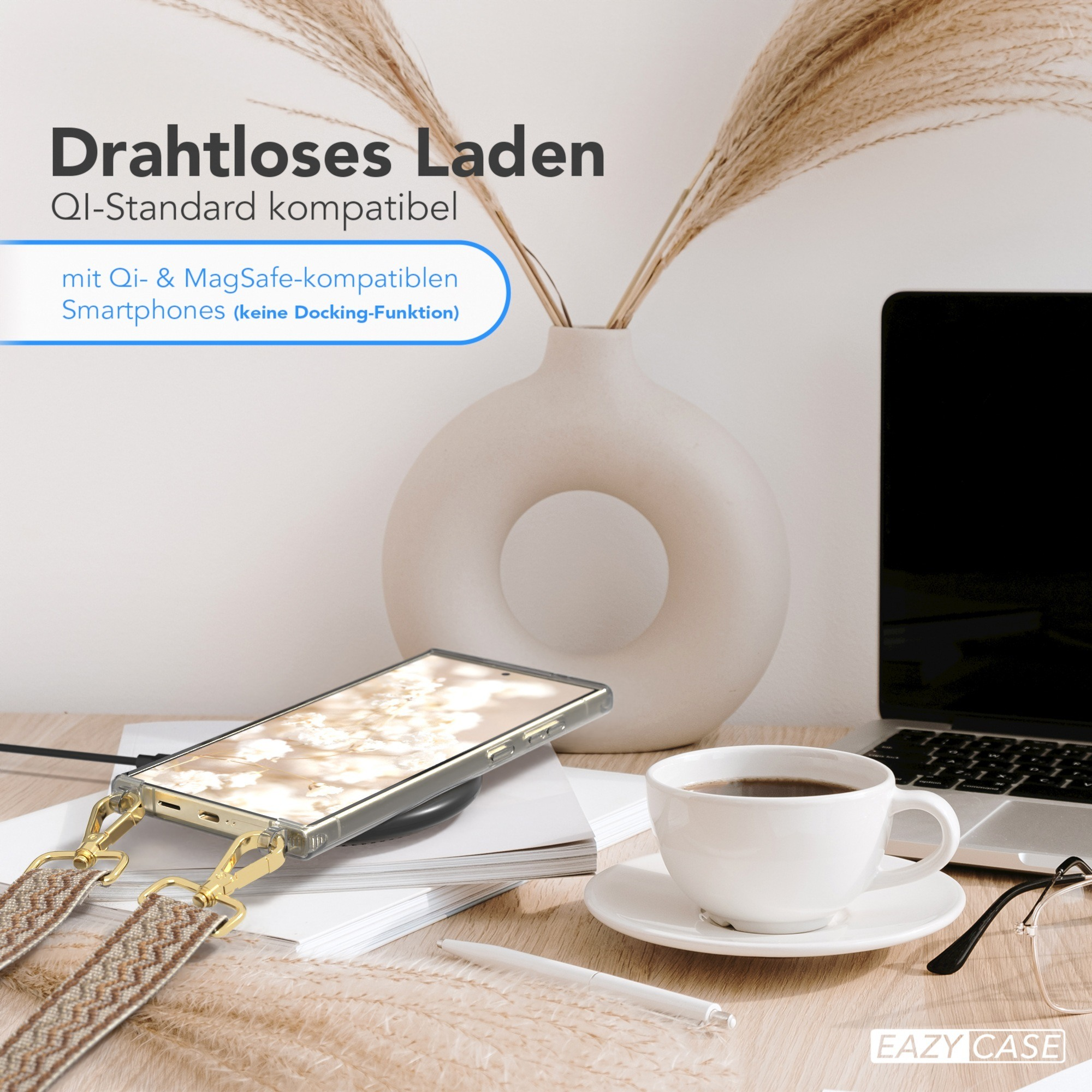 Ein Telefon wird kabellos geladen. Auf dem Schreibtisch befinden sich ein Laptop, eine Tasse Kaffee und eine Vase.