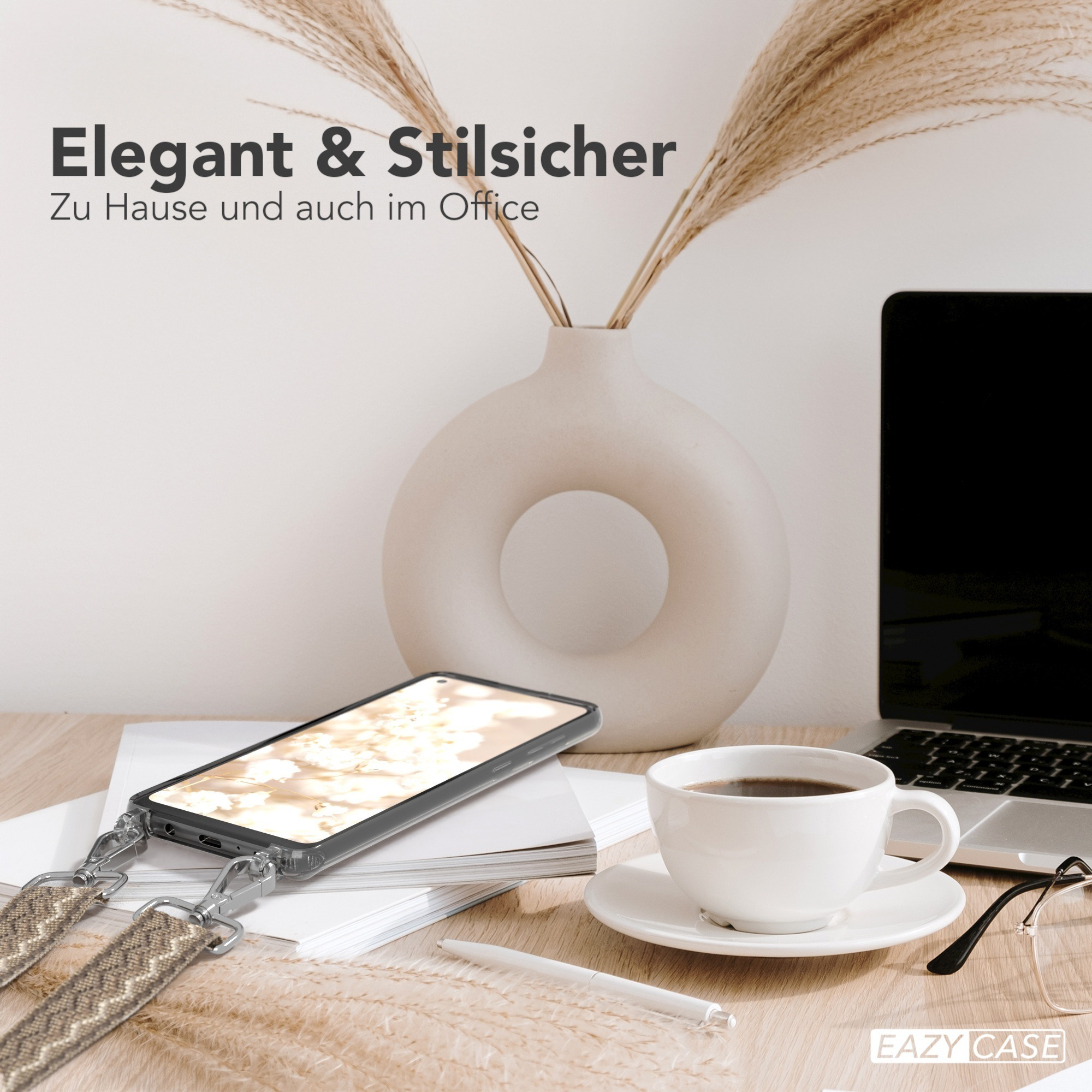 Telefon auf einem Schreibtisch mit Kaffeetasse, Brille und Blumen. Das Telefon hat einen Riemen.