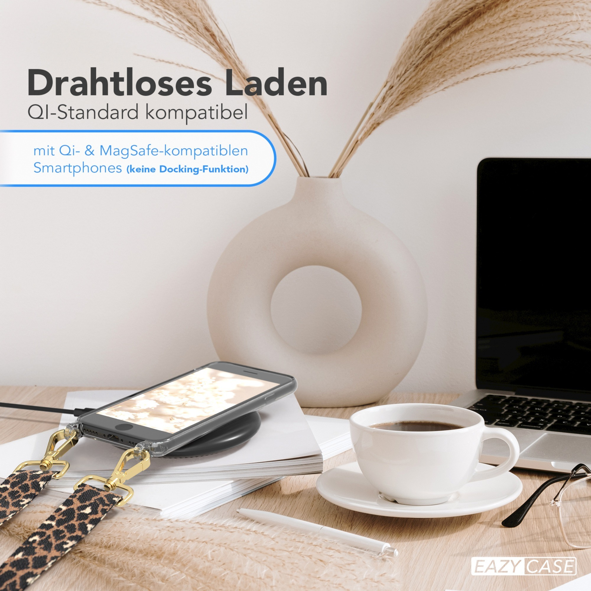 Telefon lädt kabellos, Kaffee und Vase mit Schilf auf einem Holztisch.