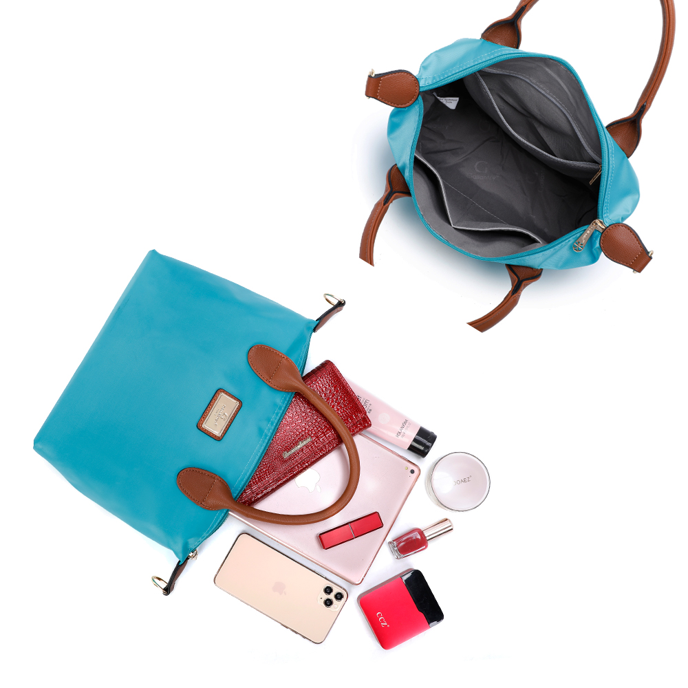 Bolso de mano azul abierto con contenido: cartera, cosméticos, teléfono y otros artículos.
