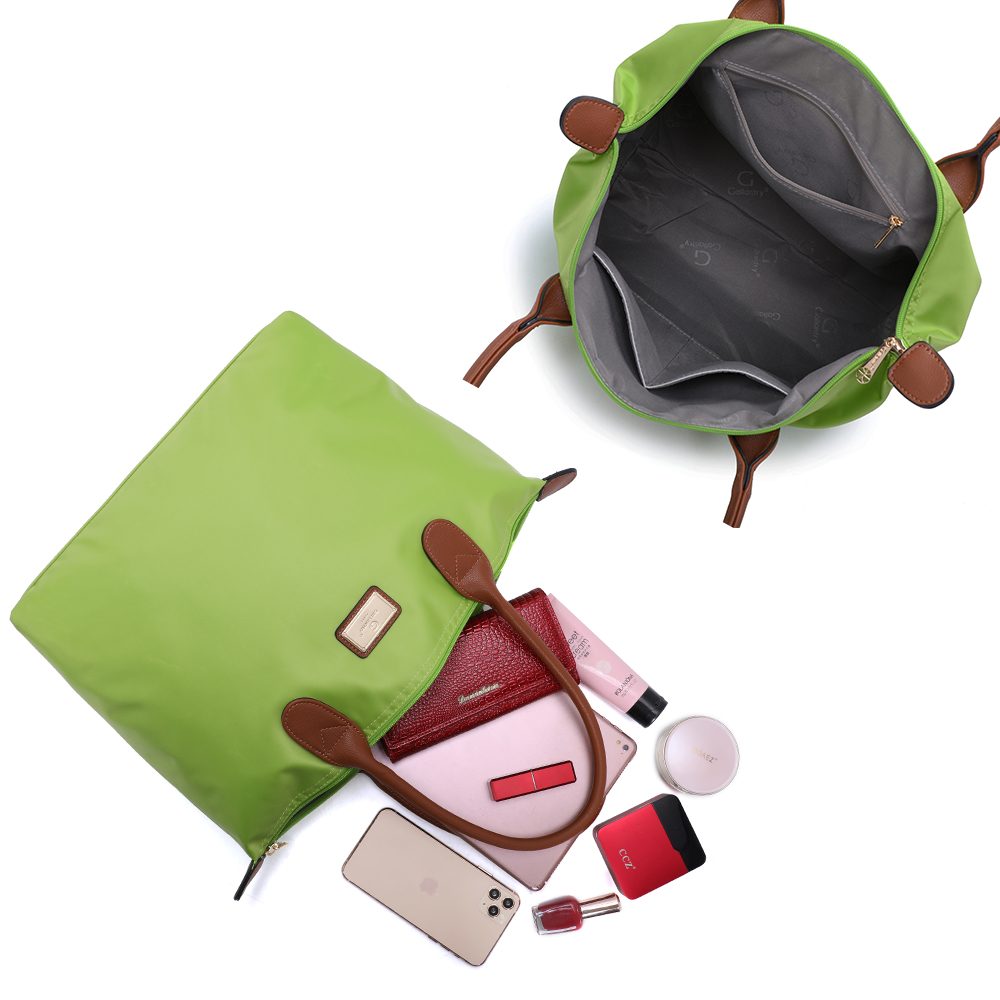 Eine grüne Tasche mit braunen Griffen ist geöffnet und zeigt den Inhalt und eine andere Tasche.