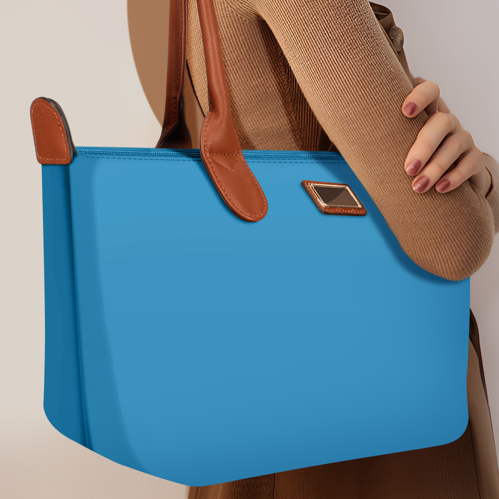 Bolso tote azul con asas y detalles de cuero marrón, sostenido por una mujer.