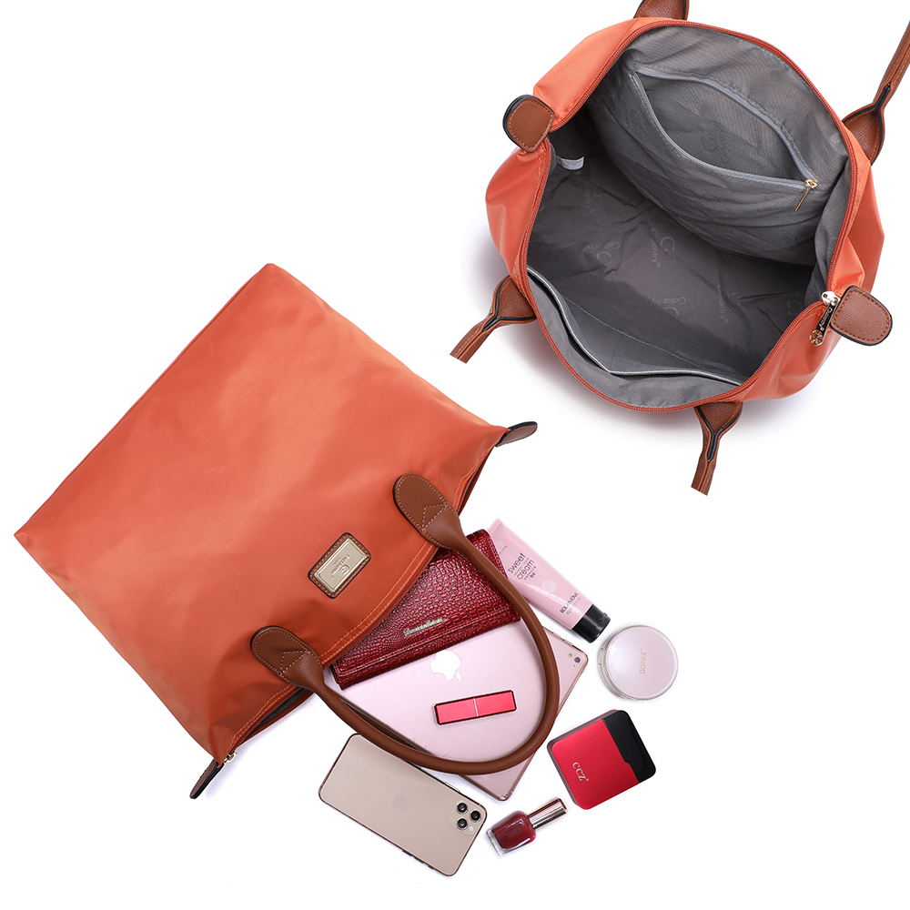 Zwei orange Tragetaschen, eine offen mit Inhalt: Geldbörse, Kosmetik, Handy und Make-up.