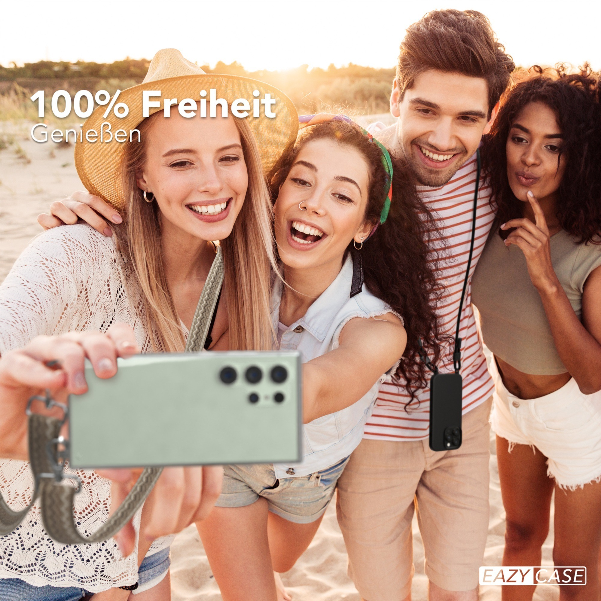 Vier lächelnde Personen, die ein Selfie am Strand mit einem Telefon und einem Lanyard machen.