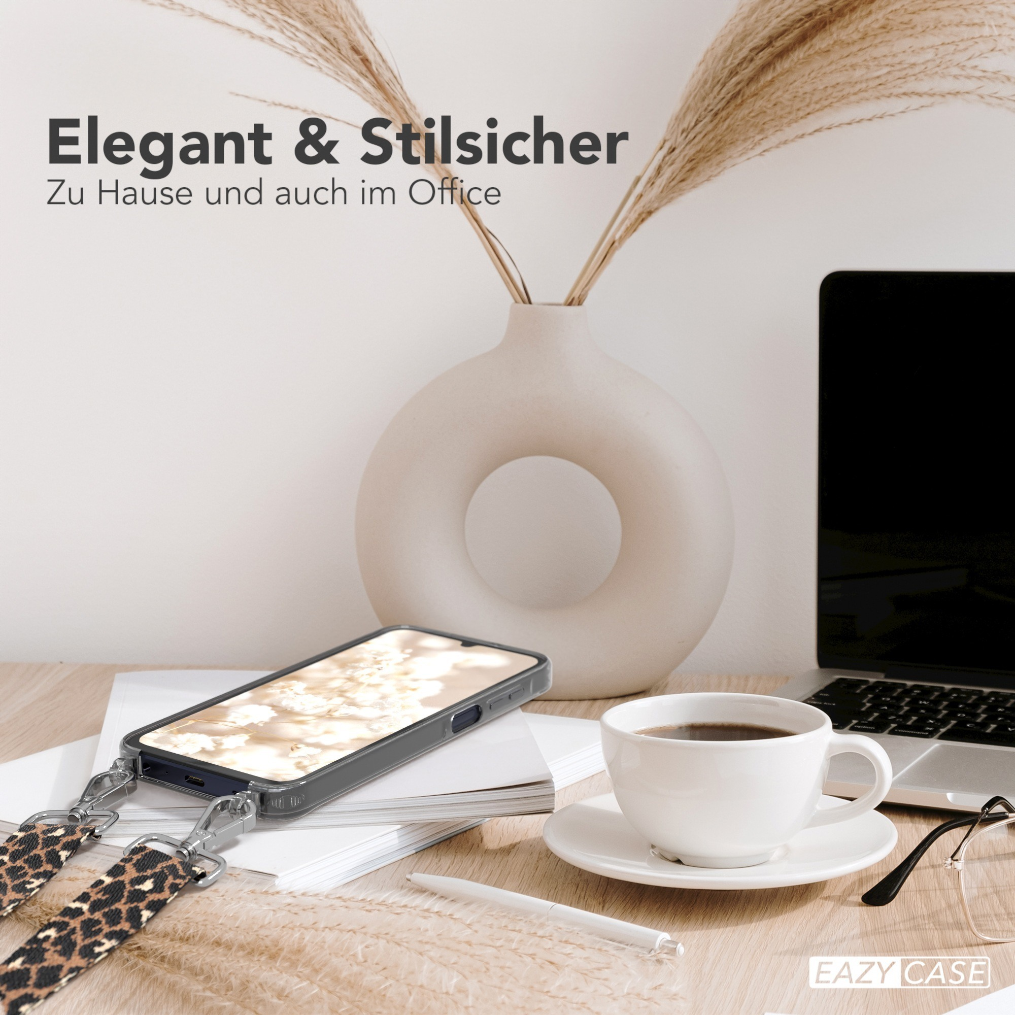 Telefon mit Leopardenband auf dem Schreibtisch, Kaffeetasse, Laptop und Vase mit Pflanzen. Elegant und stilvoll.