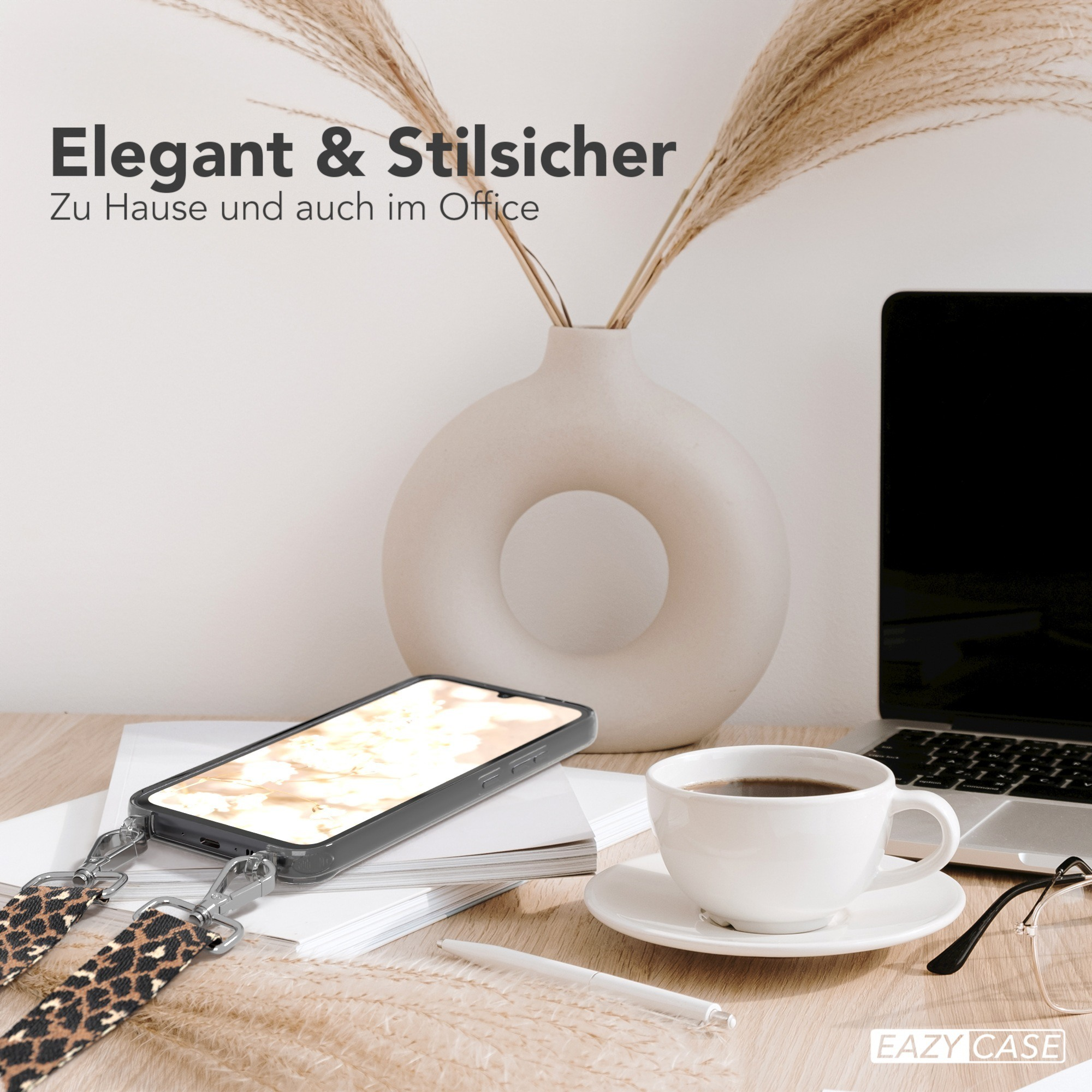 Telefon mit Leopardriemen, Kaffee, Laptop und Vase auf dem Schreibtisch.