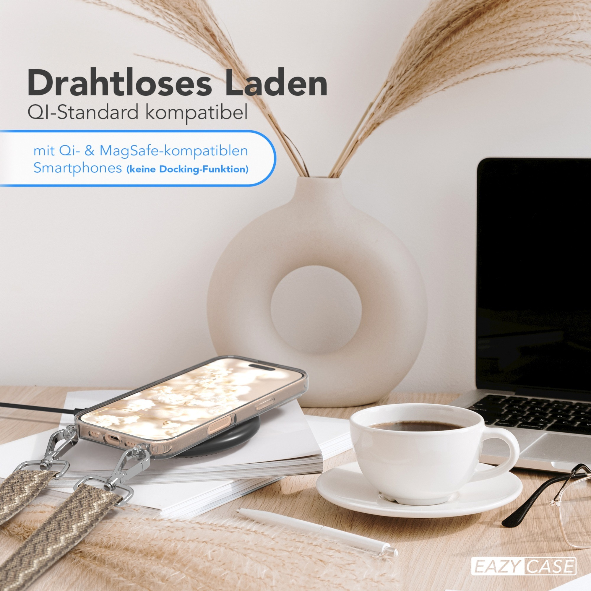 Telefon auf kabellosem Ladegerät, Kaffeetasse, Vase, Laptop und Zubehör auf einem Holzschreibtisch.