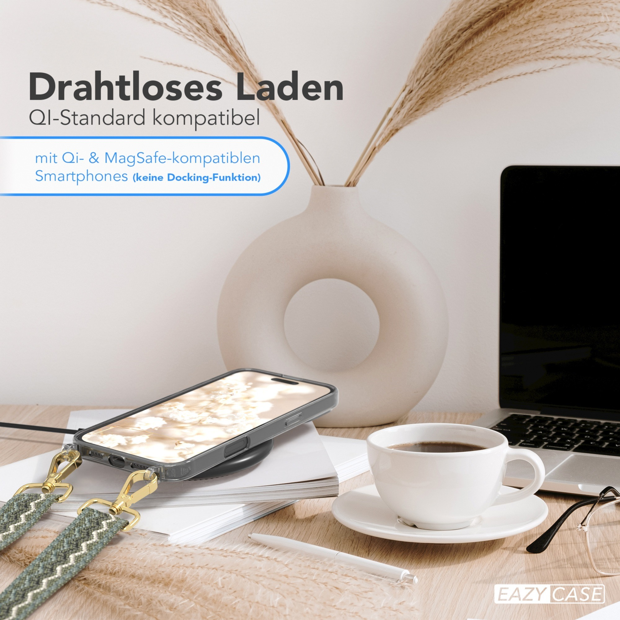 Ein Telefon mit Hülle wird drahtlos auf einem Pad aufgeladen. Eine Tasse Kaffee, Gläser und ein Stift liegen auf dem Tisch.