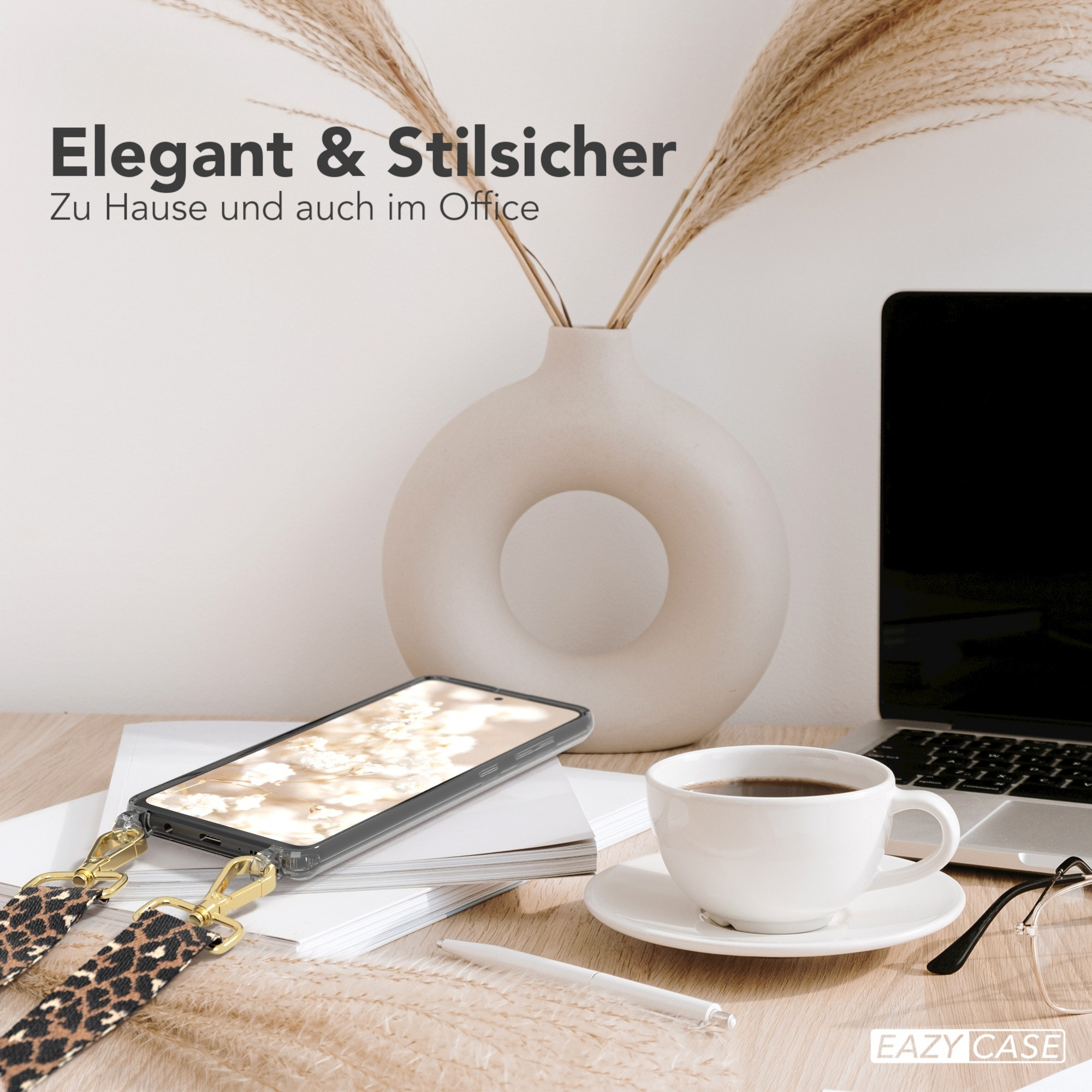 Ein Telefon mit Leopardenmusterriemen auf einem Schreibtisch mit einer Tasse Kaffee. Ein Laptop und eine Vase befinden sich im Hintergrund.