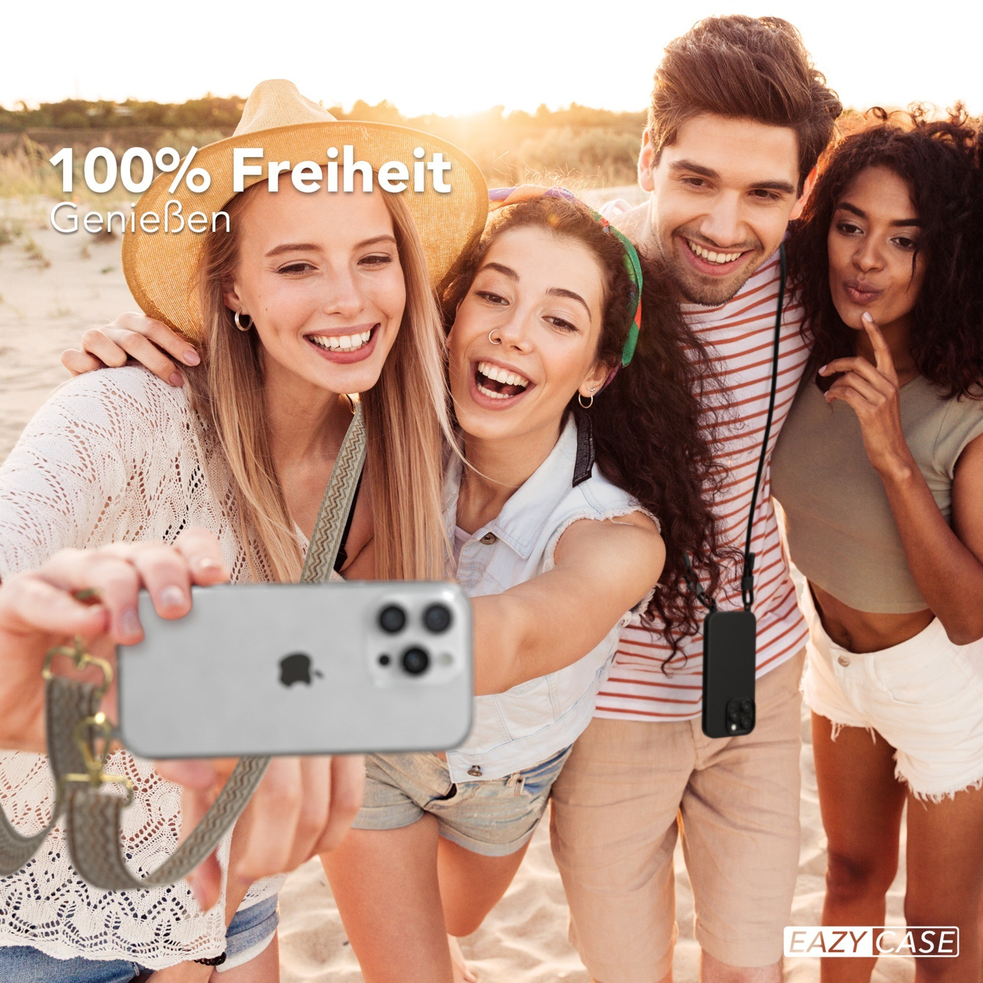 Vier Personen machen ein Selfie. Zwei halten das Telefon. Sandiger Strandhintergrund.