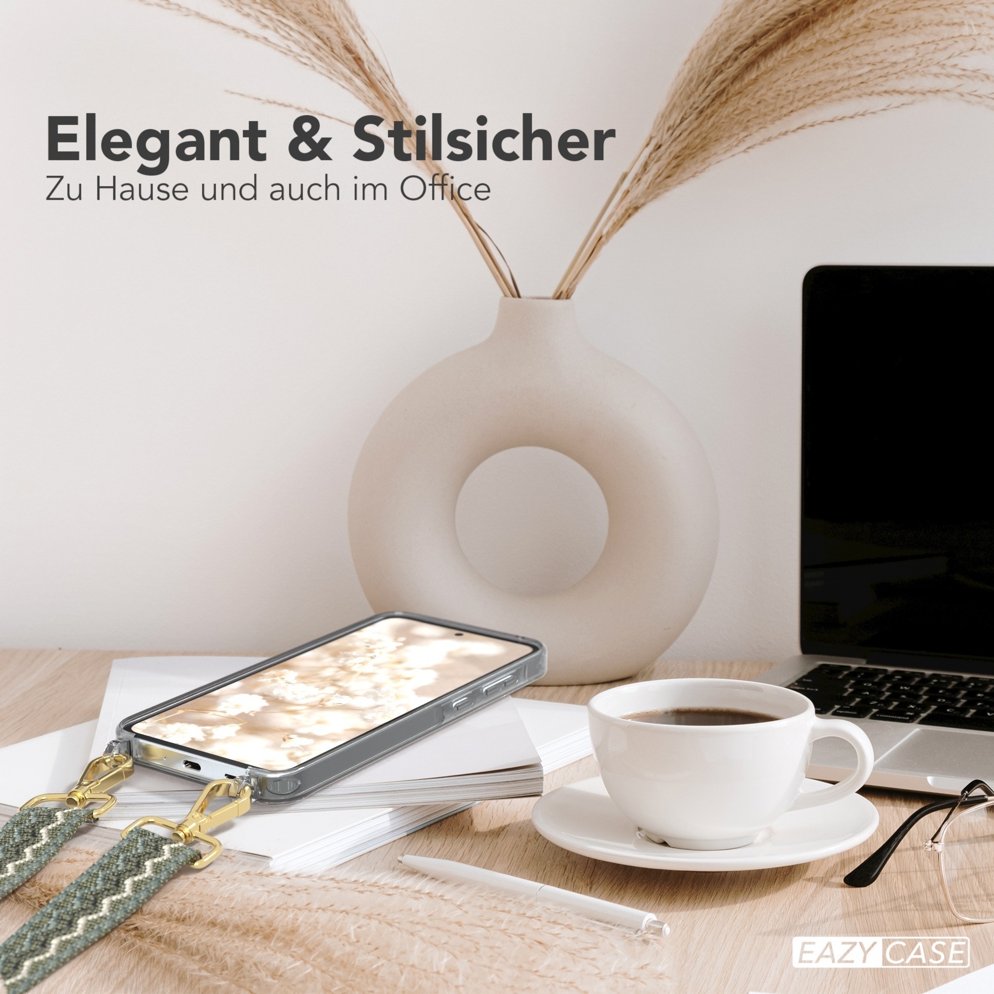 Telefon mit Trageriemen auf Holztisch. Kaffeetasse, Stift und Laptop stehen auf dem Tisch.