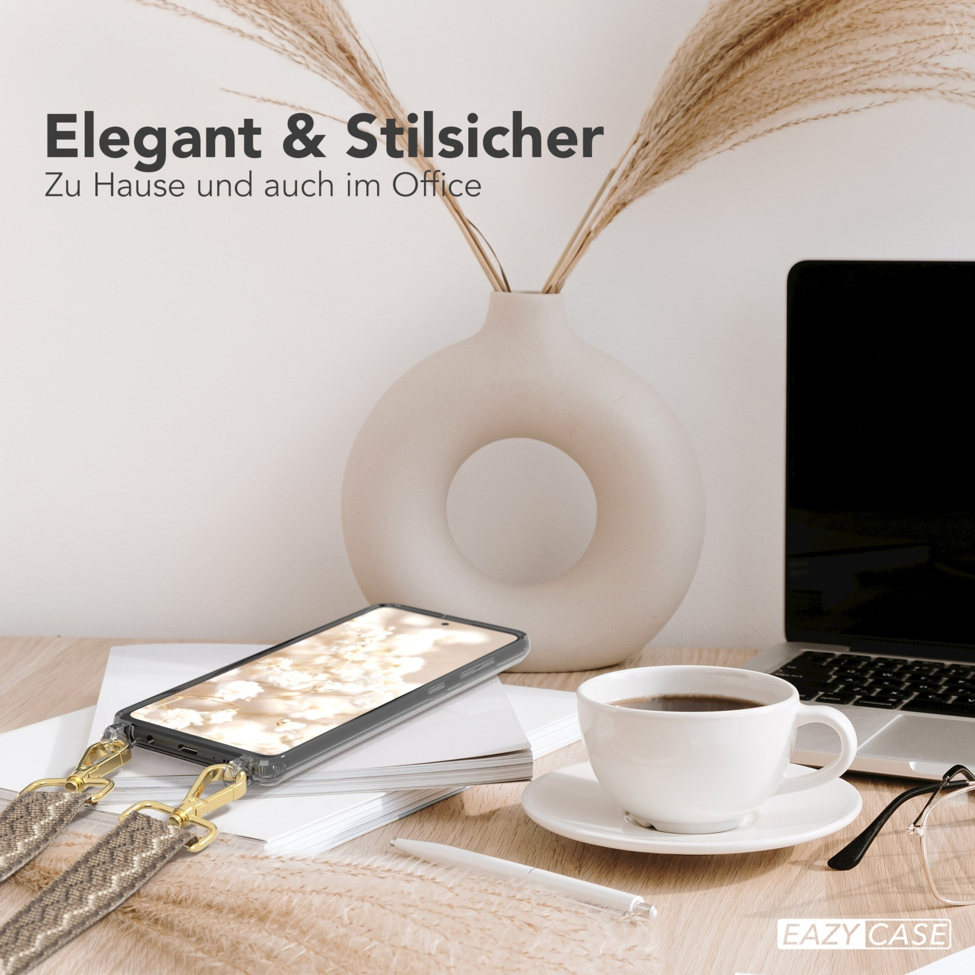 Büroszene: Handyhülle mit Trageriemen, Kaffeetasse, Laptop und Blumen auf einem Schreibtisch.