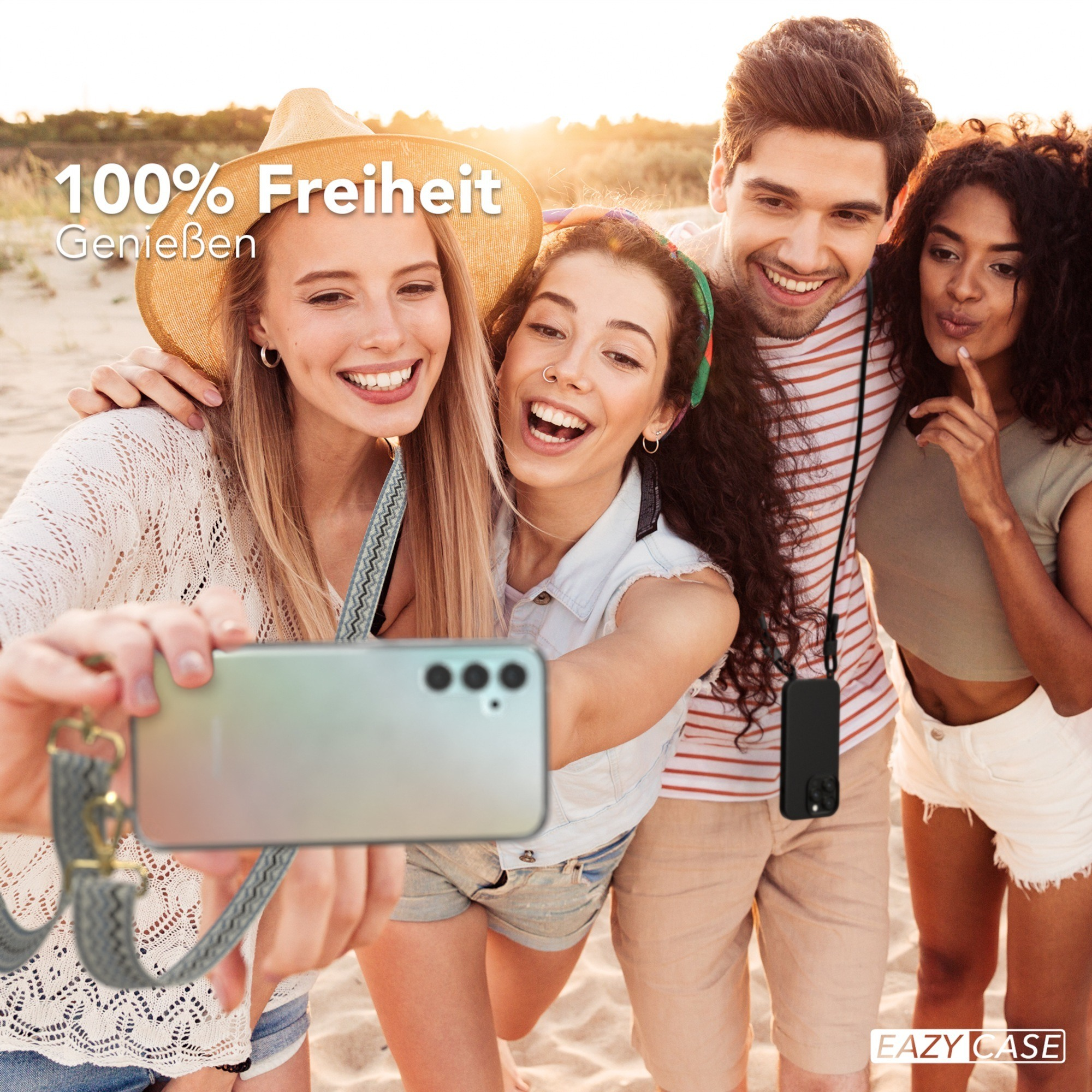Vier Personen machen ein Selfie am Strand. Sie lächeln und halten ein Telefon mit einem Gurt.