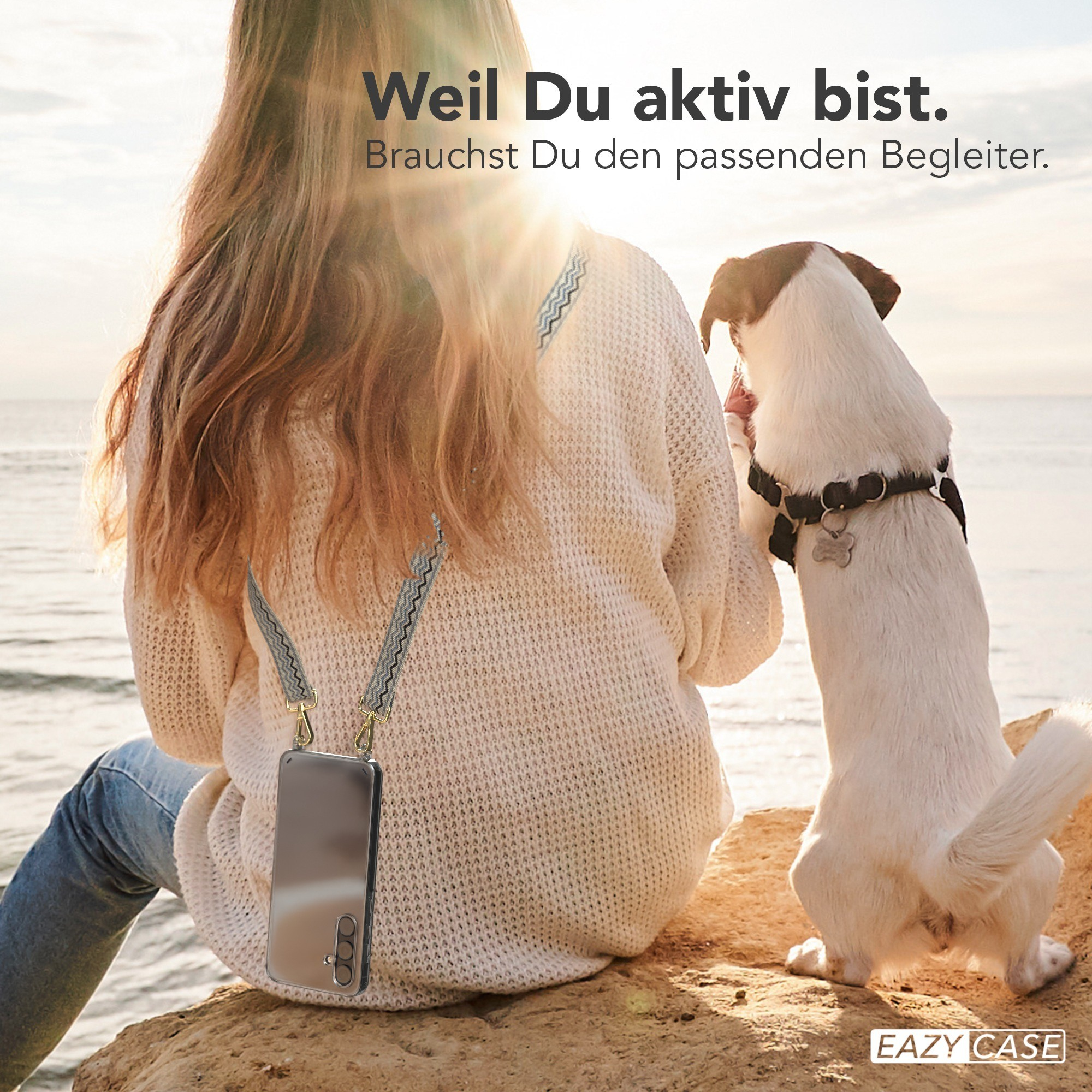 Eine Frau und ein Hund sitzen am Wasser, der Hund schaut nach oben.