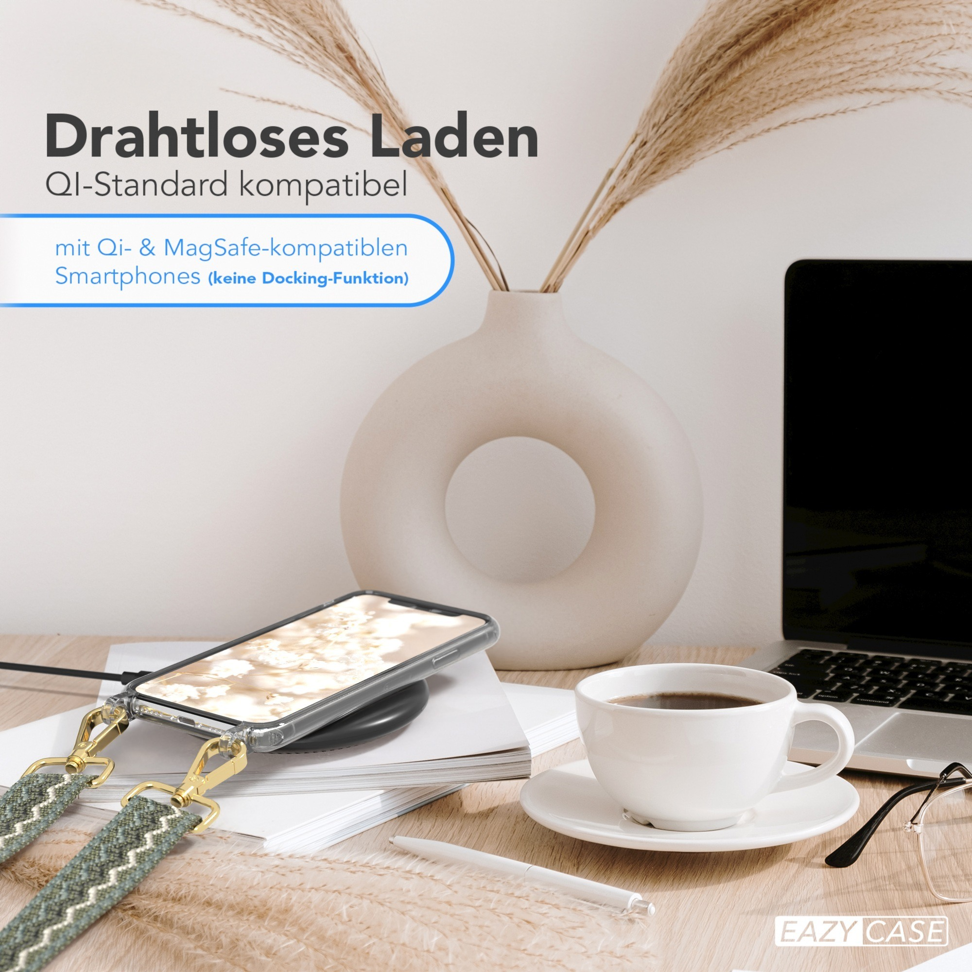Telefon mit Riemen lädt auf Qi-Ladegerät. Kaffeetasse und Laptop auf dem Schreibtisch. Text: Drahtloses Laden, Qi-Standard kompatibel.