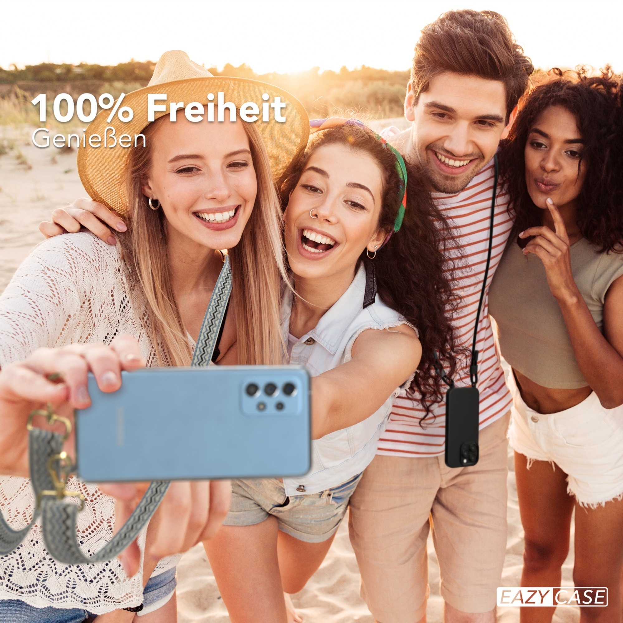 Vier Personen machen ein Selfie am Strand. Sie lächeln und halten ein Telefon mit einem Gurt.