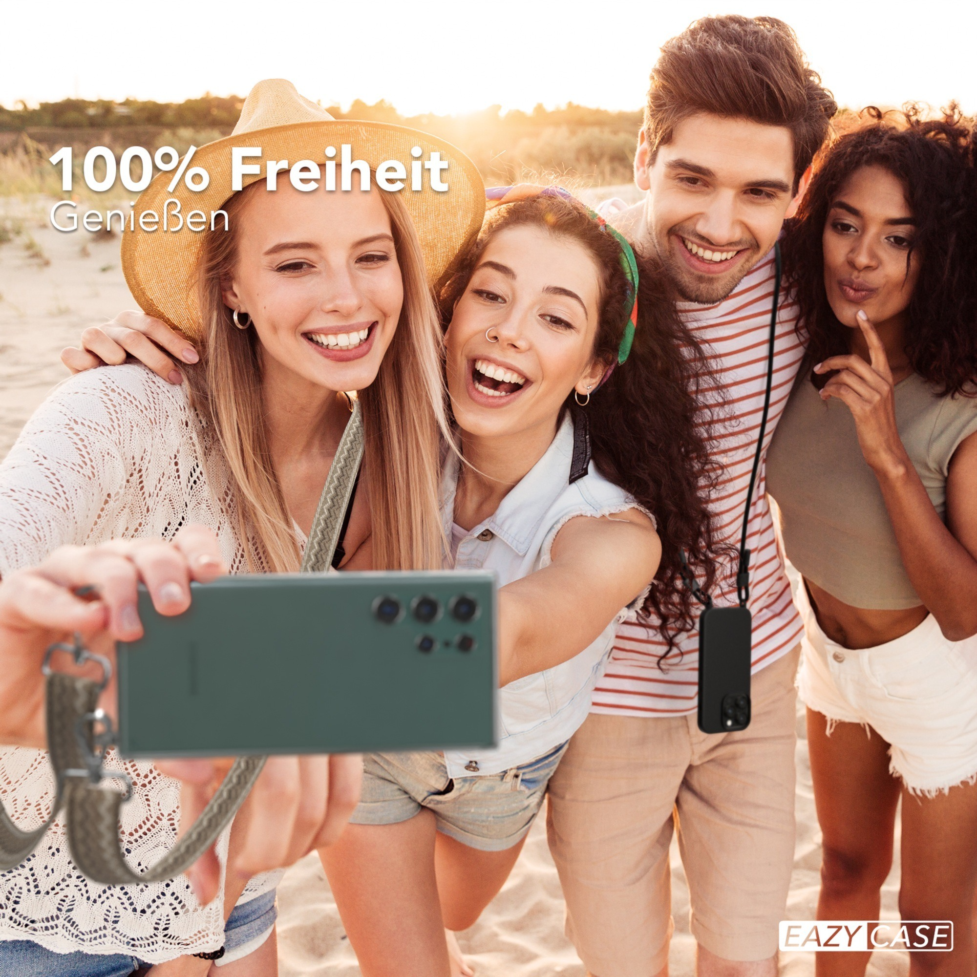 Vier Personen machen ein Selfie. Einer hält ein Telefon mit Riemen. Alle lächeln.