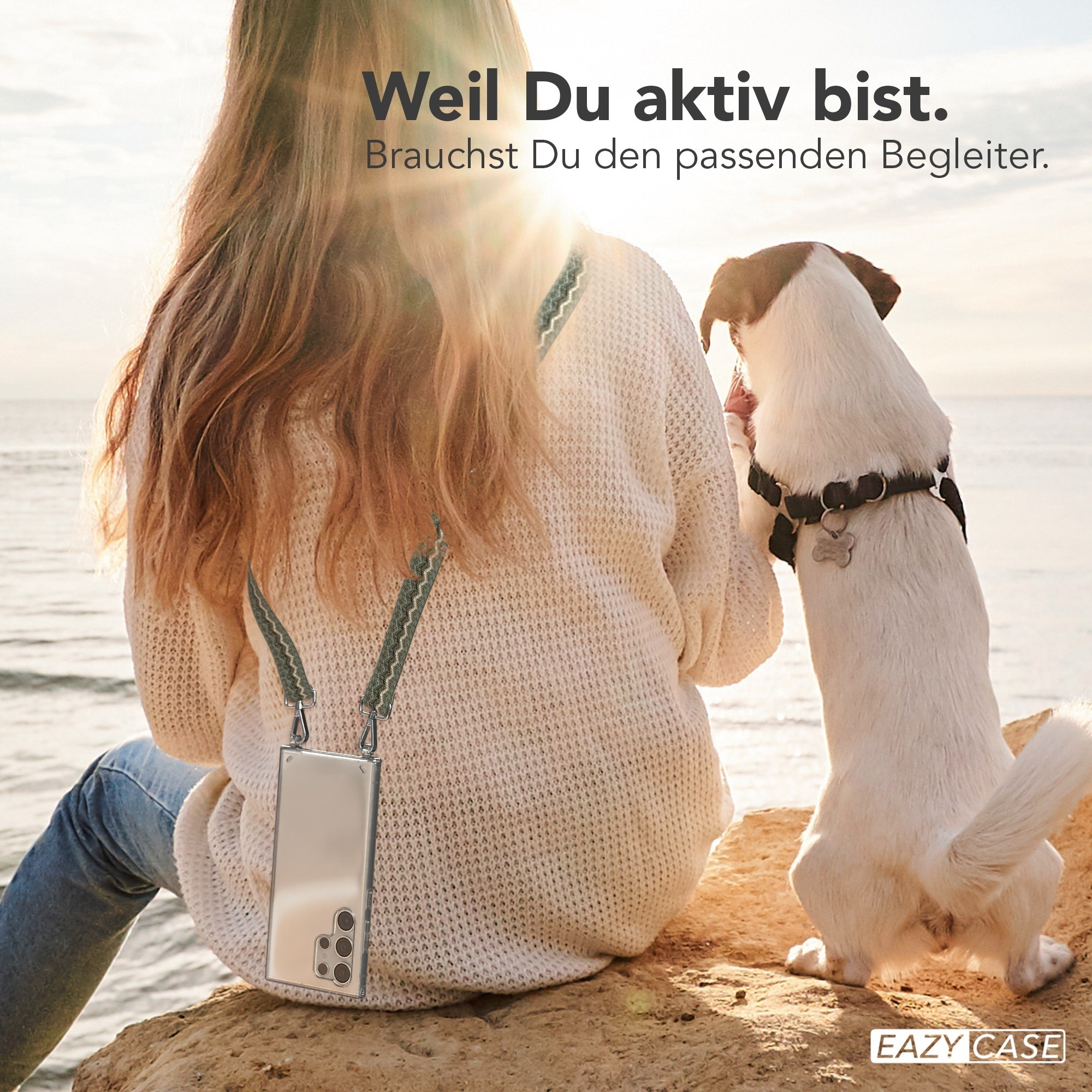 Frau mit Handyhülle und Hund am Strand.