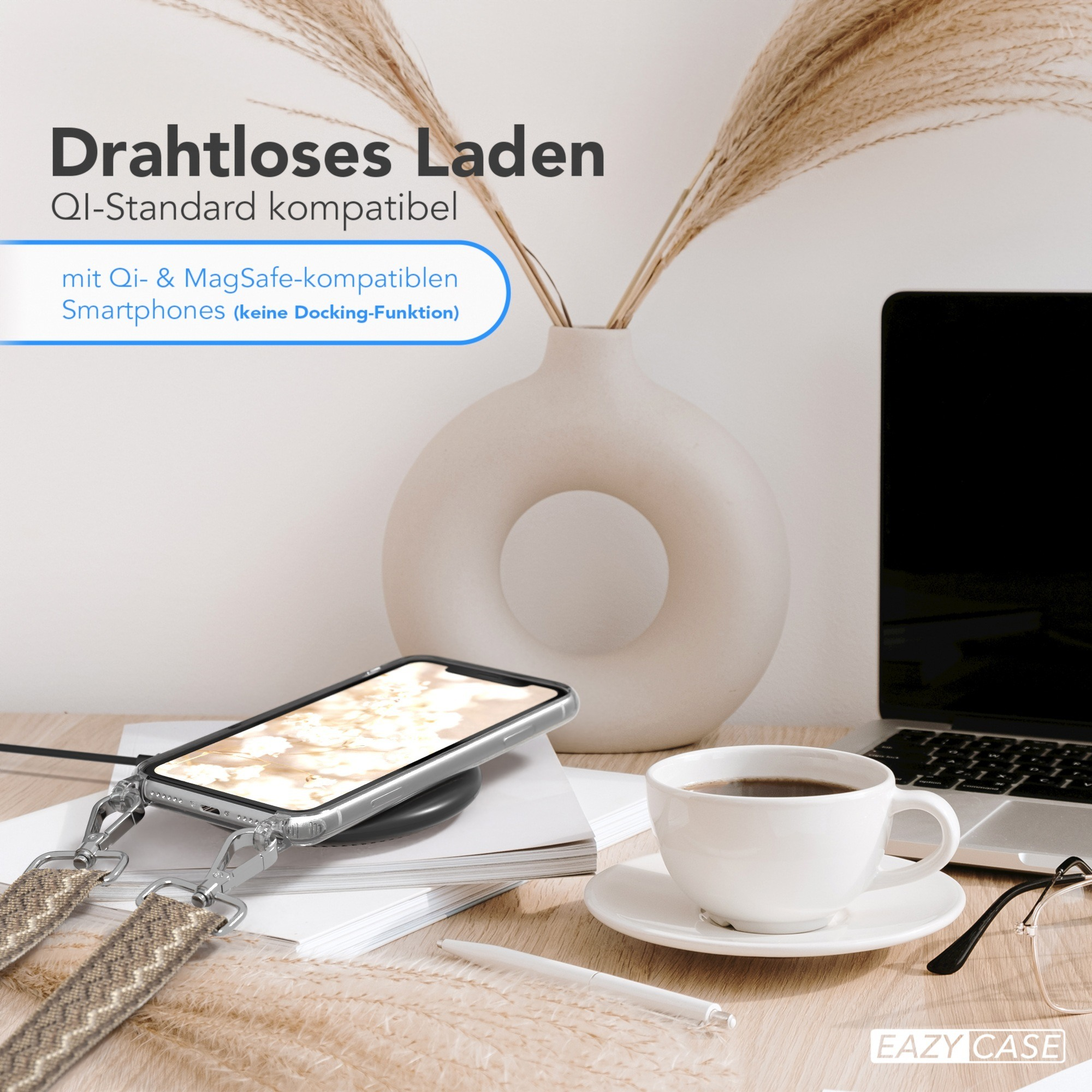 Schreibtisch mit Telefon auf kabellosem Ladegerät. Kaffeetasse, Stift, Brille und Blumen sind ebenfalls vorhanden.