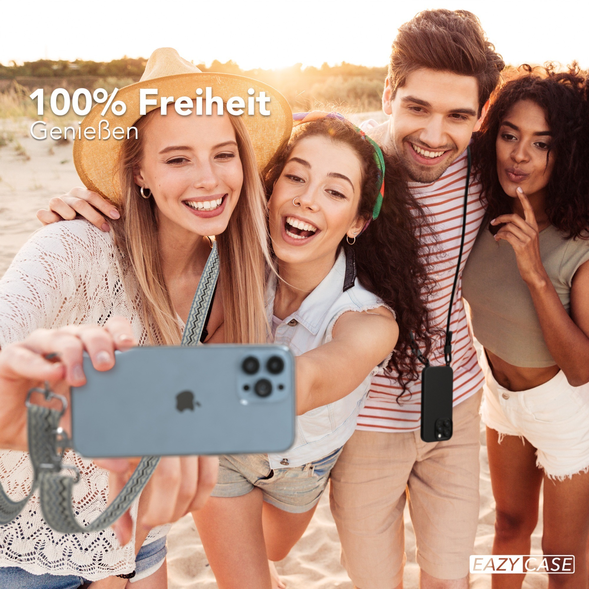 Vier lächelnde Personen machen ein Selfie am Strand mit einem Telefon und Gurt.