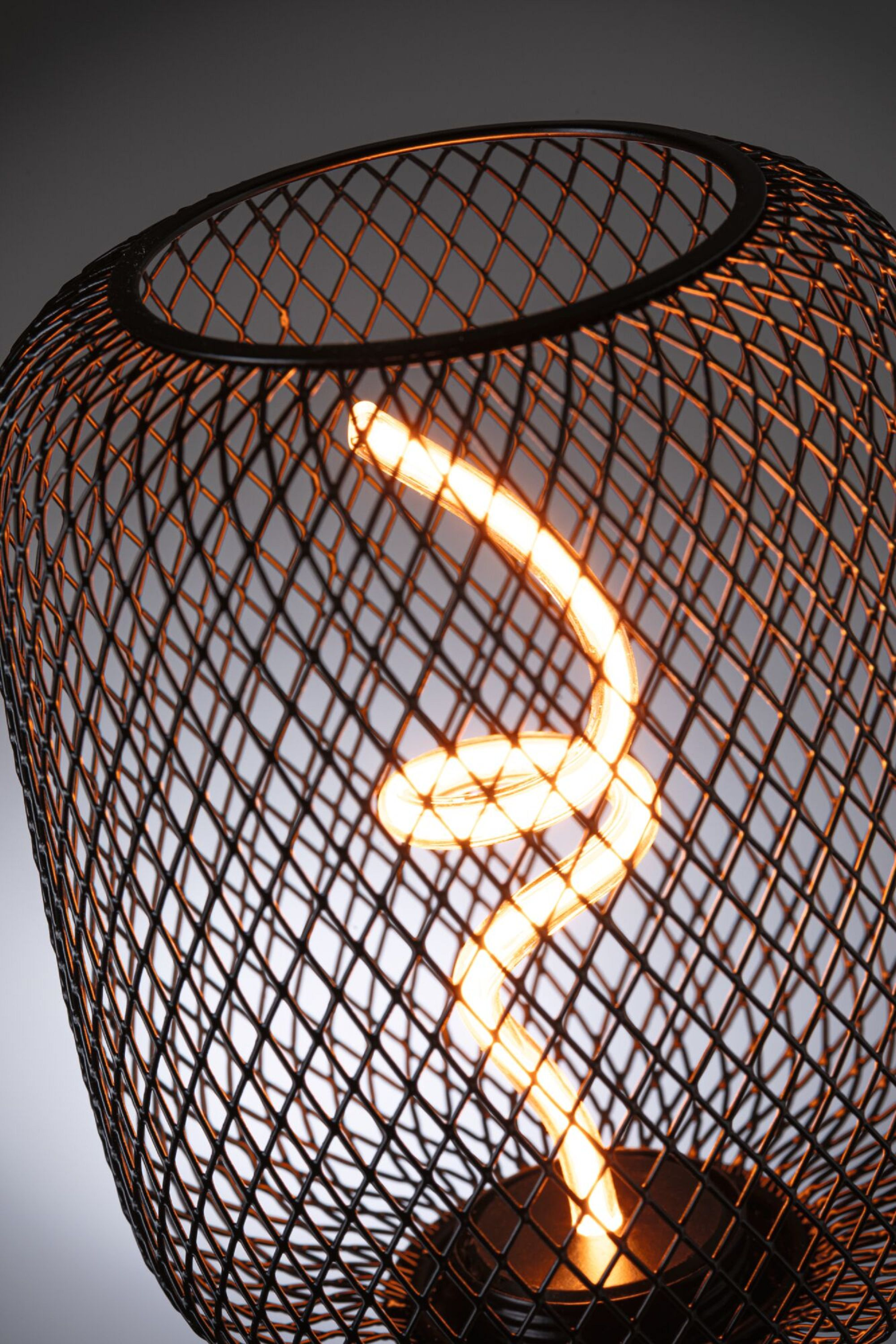 Czarna metalowa lampa z świecącym spiralnym światłem w środku.