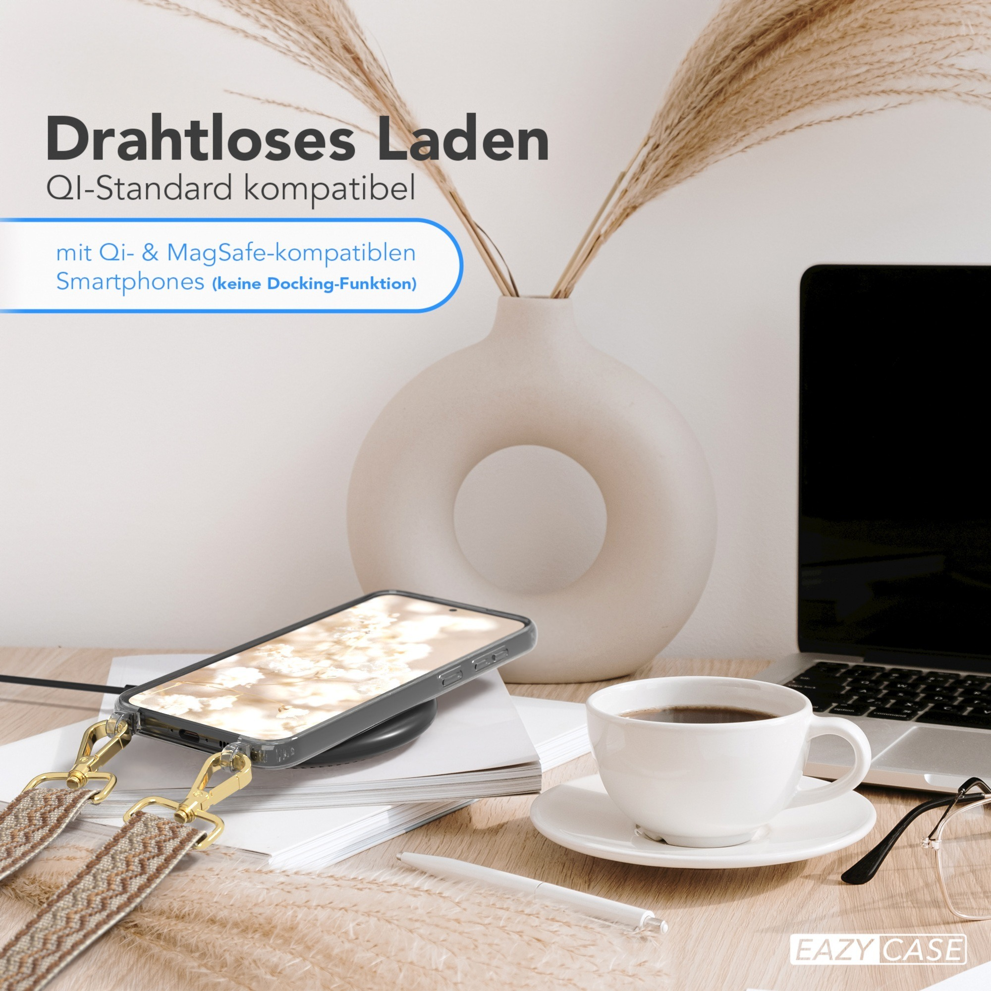 Telefon auf kabellosem Ladegerät, mit Kaffee und Laptop. Vase mit Zweigen.