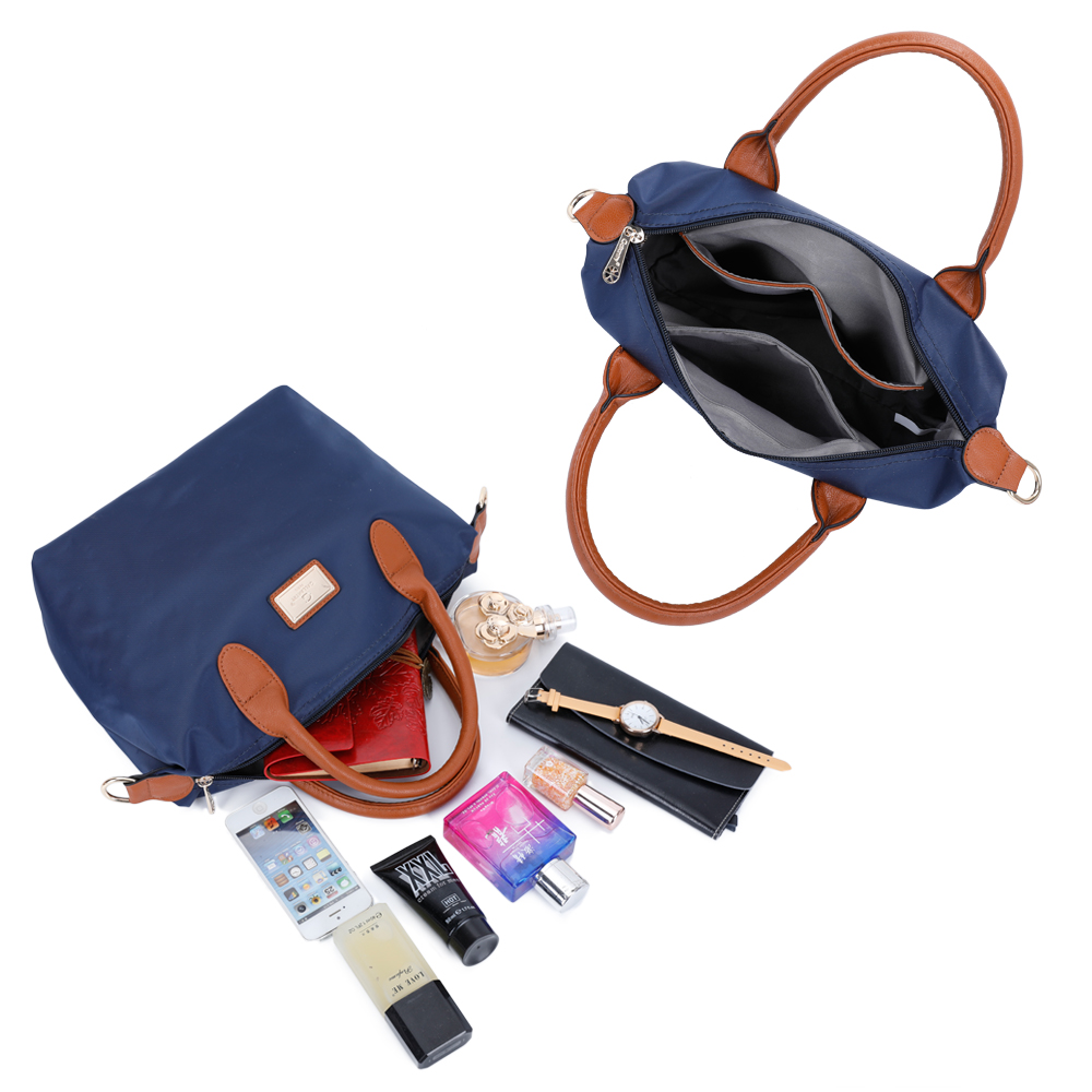 Un bolso azul con asas marrones y objetos en la mesa: teléfono, perfume, cartera.