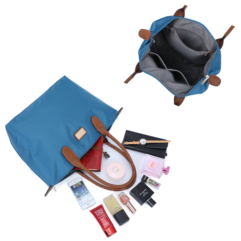 Eine blaue Tragetasche, offen, mit verschiedenen herausquellenden Gegenständen. Enthält Telefon, Make-up und Parfüm.