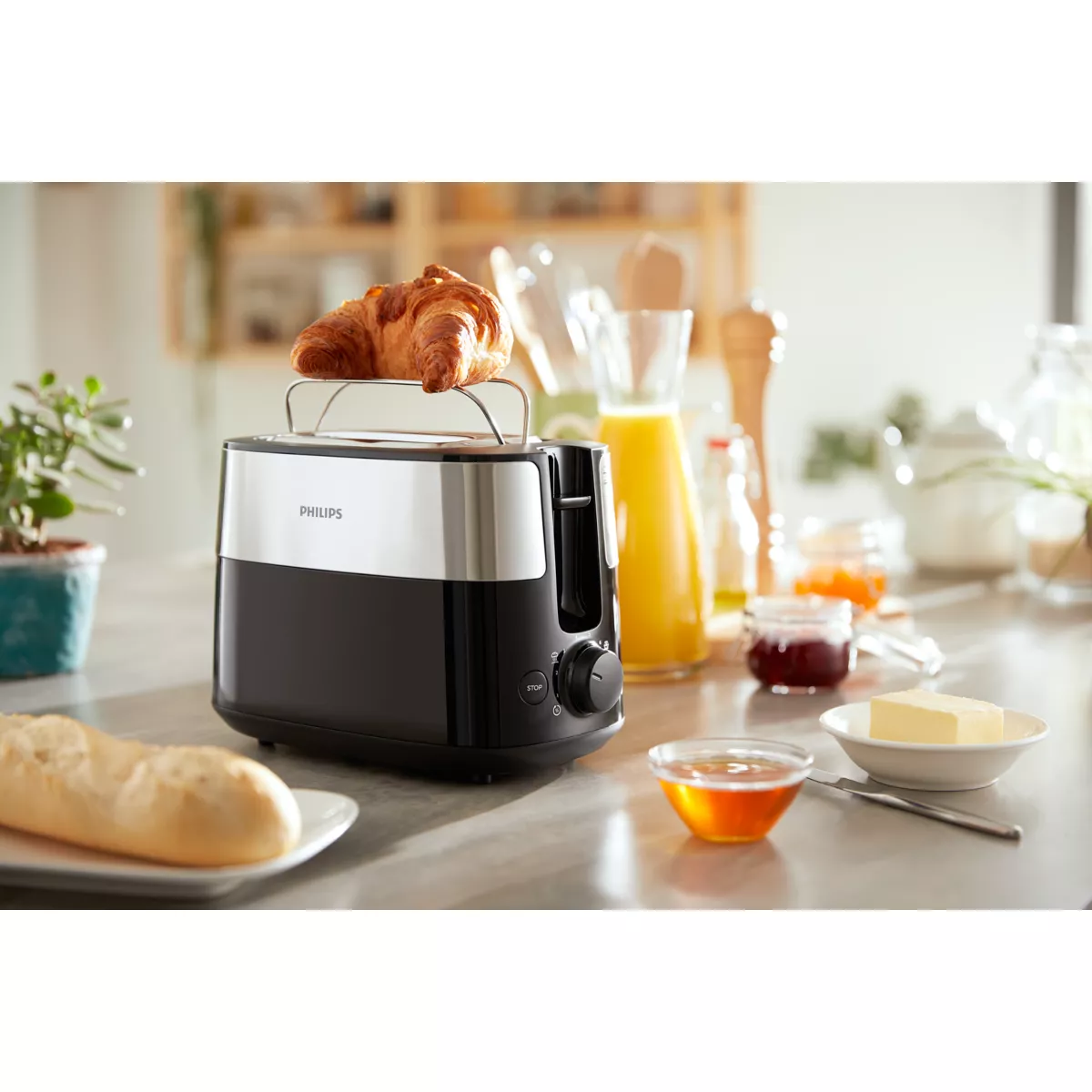 Toaster mit Croissant. Butter und Marmelade stehen auf dem Tisch. Küchenhintergrund.