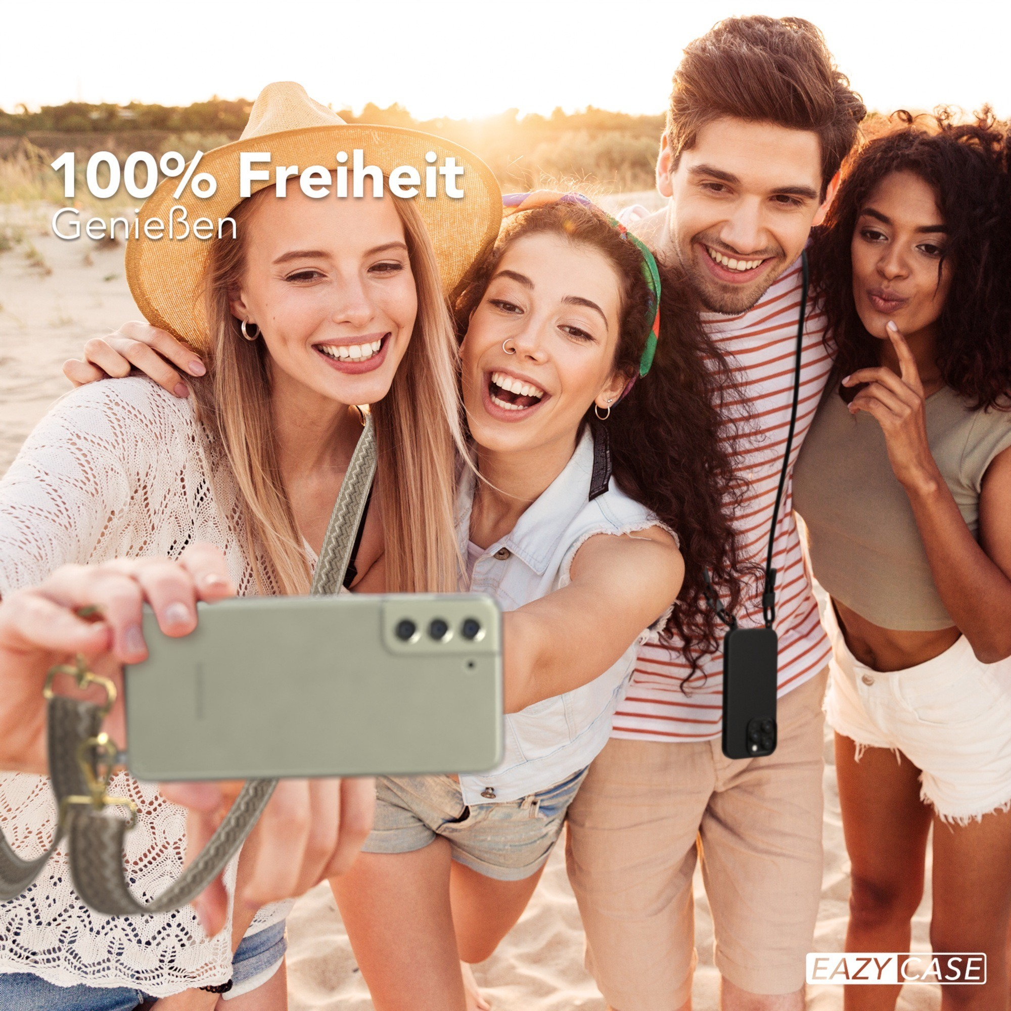 Vier Freunde machen Selfie am Strand. Einer hält Telefon mit Band. Sonne und Sand im Hintergrund.