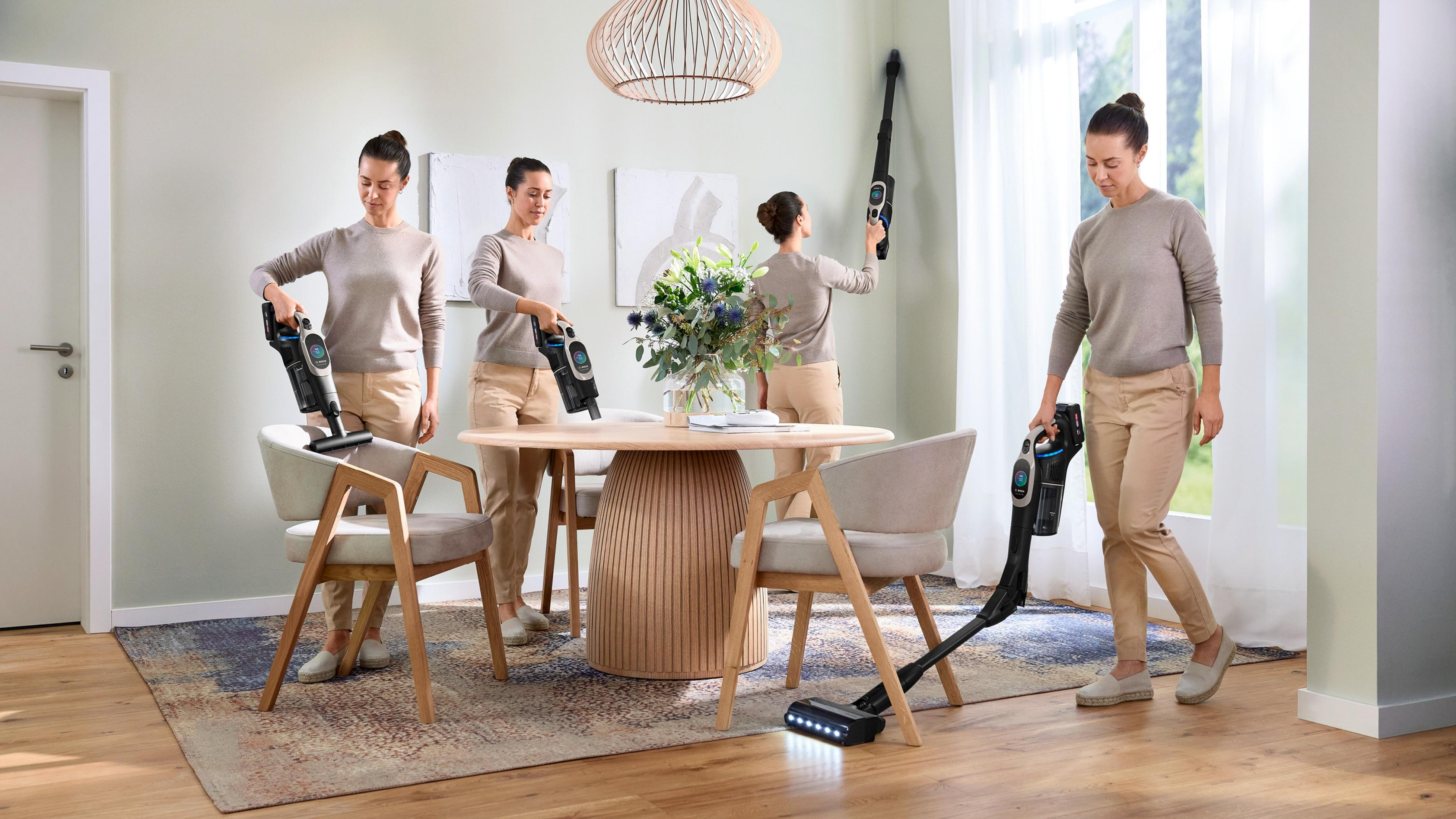 Frau benutzt Staubsauger in einer häuslichen Umgebung, mehrere Winkel. Sauberes Zimmer mit Holztisch.