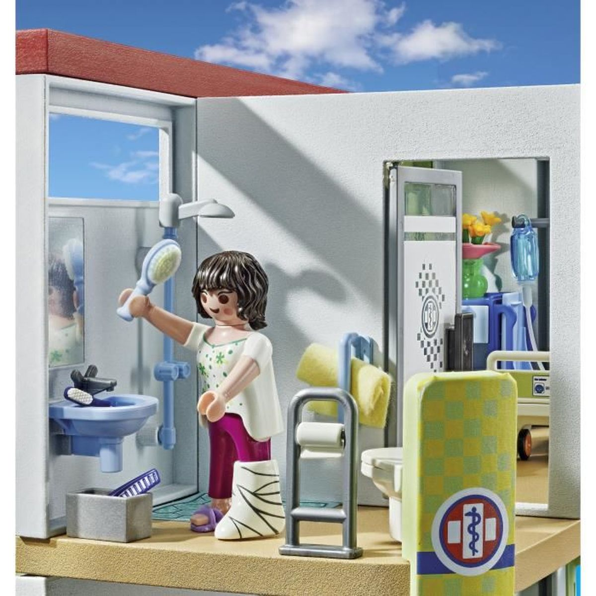 Scena Playmobil in una stanza d'ospedale. Una donna ingessata tiene una spazzola.