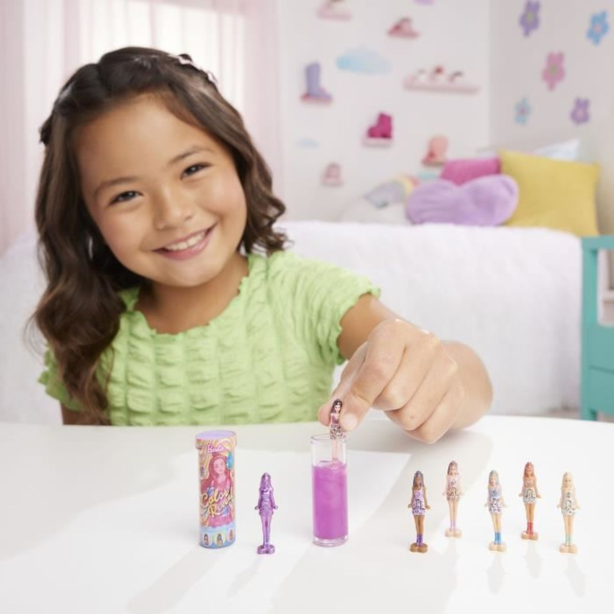 Mädchen hält Mini-Puppe, mit anderen Puppen und einer Flasche.