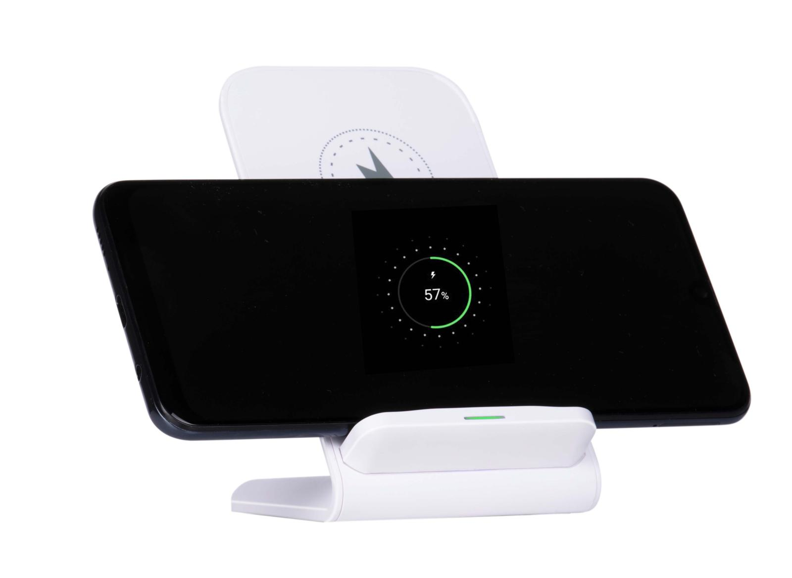 Een smartphone laadt draadloos op een witte oplaadstandaard en toont de voortgang.