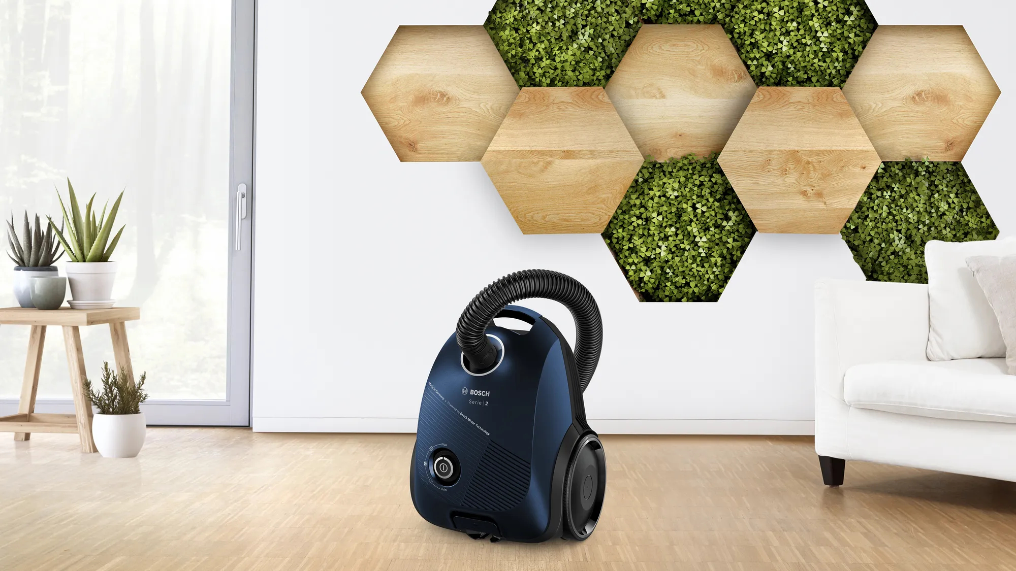 Aspiradora azul sobre suelo de madera contra pared blanca con paneles decorativos de madera.
