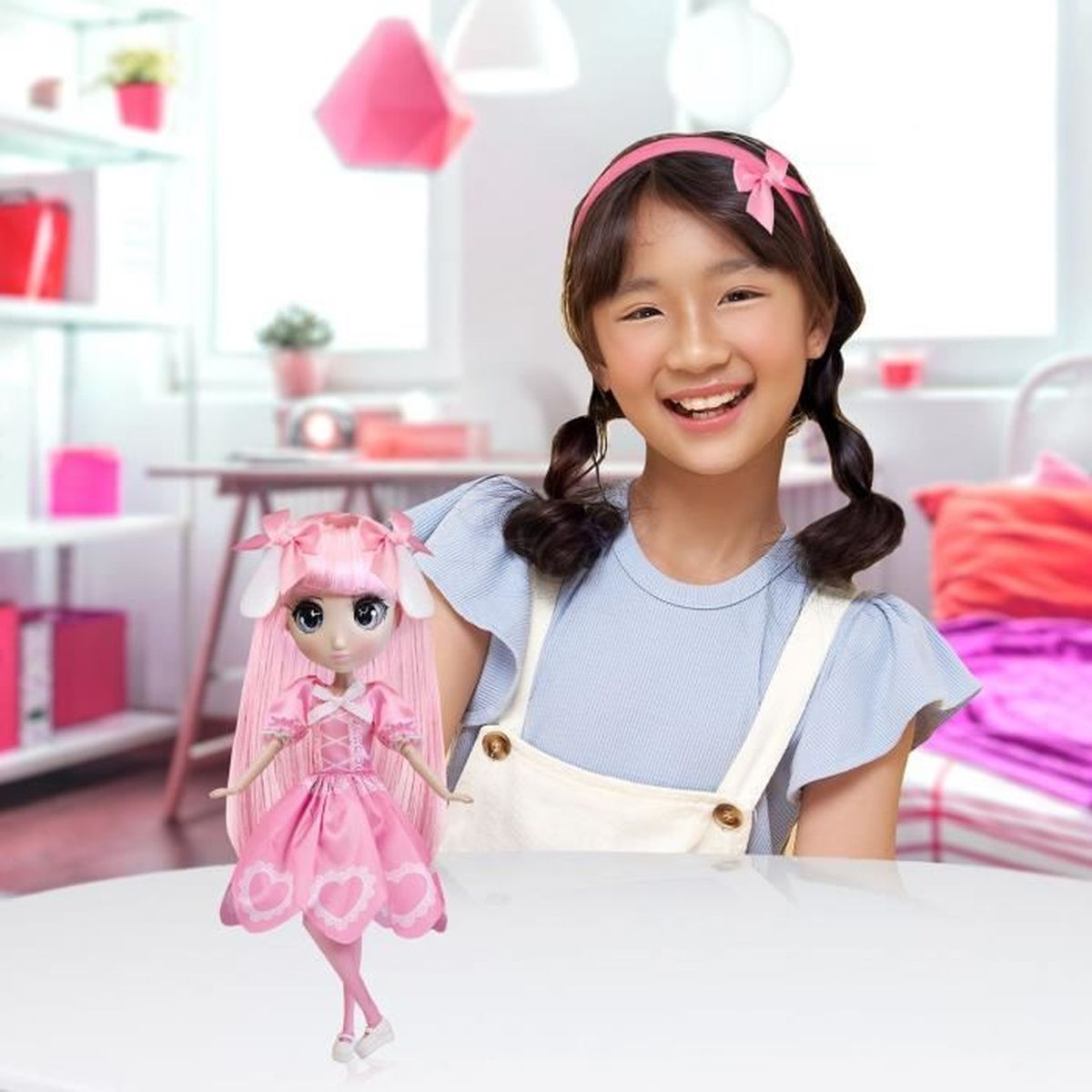 Ein lächelndes Mädchen mit Zöpfen steht neben einer rosa Puppe. Die Puppe hat rosa Haare und ein rosa Kleid.