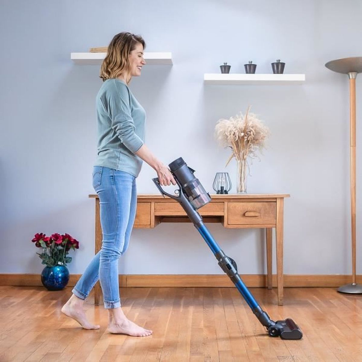 Donna che aspira un soggiorno con un aspirapolvere senza filo.